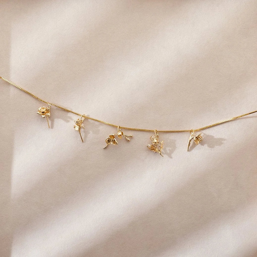 Gold necklace with floral charms on a beige background