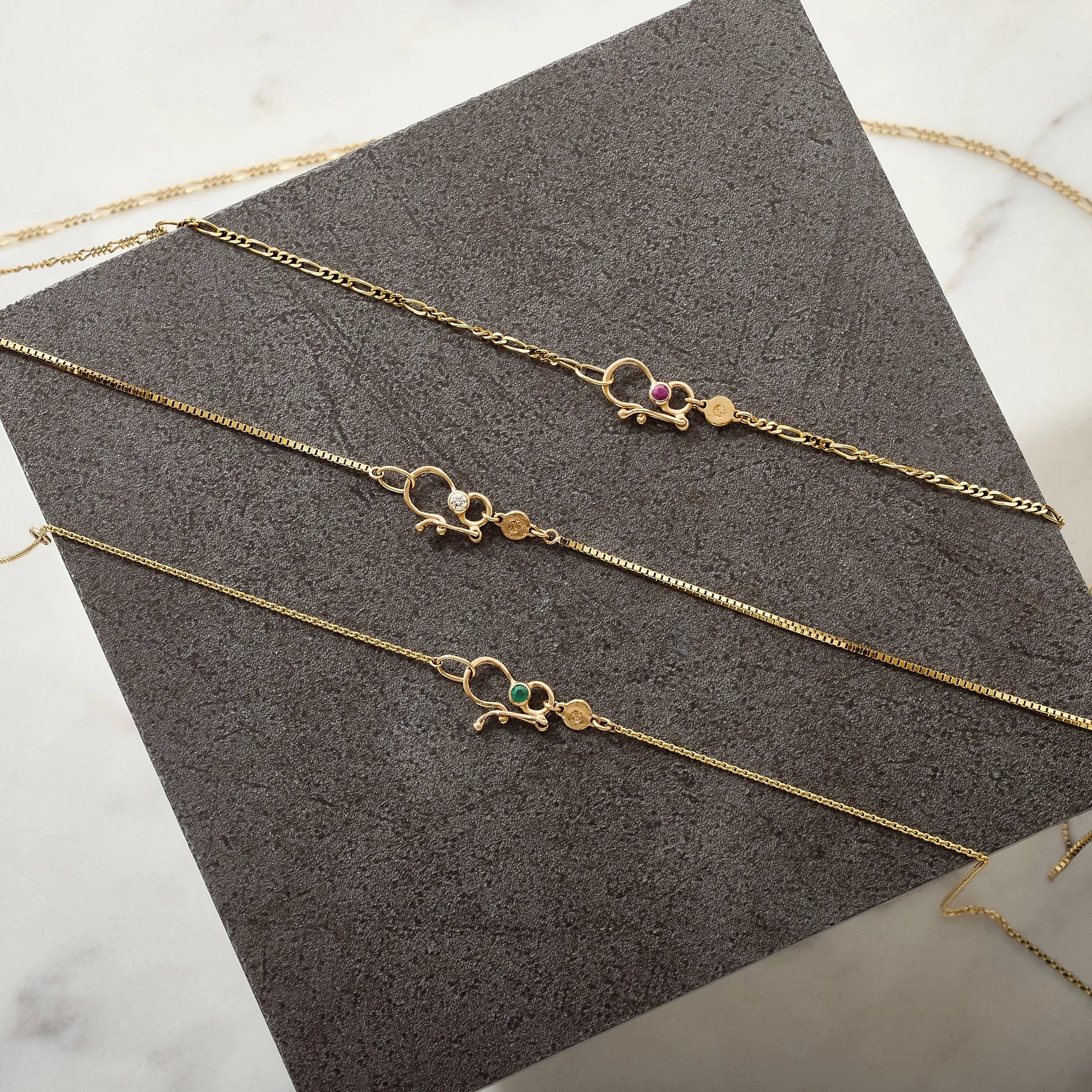 Gold necklaces with decorative clasp on a textured gray surface