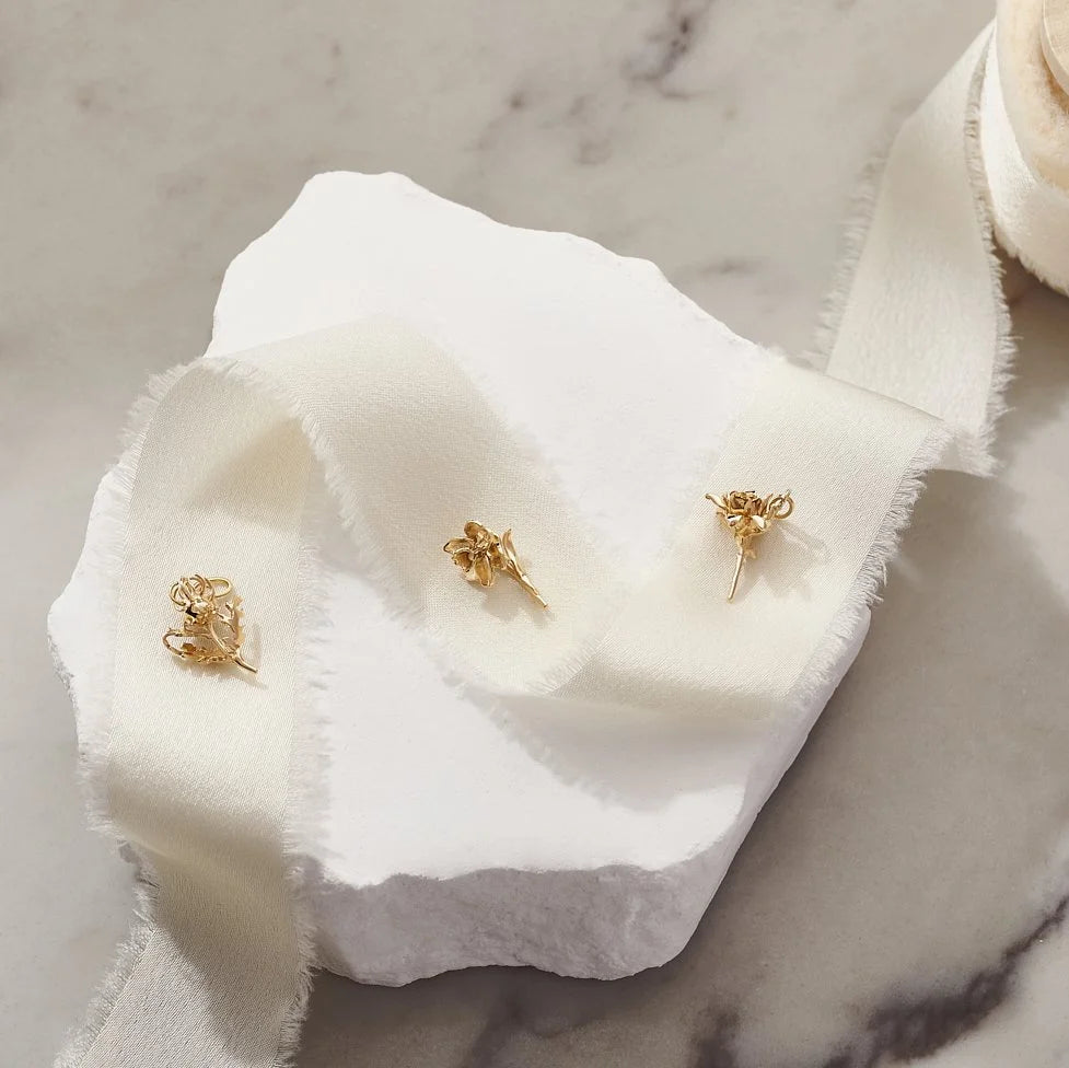 Gold charms on a white fabric with a marble background