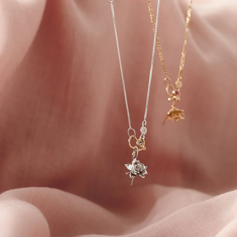 Two necklaces with floral pendants on a soft pink background
