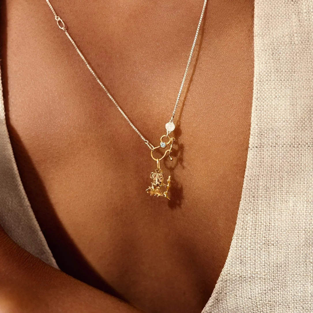 Gold necklace with a pendant on a person's neck against a neutral background