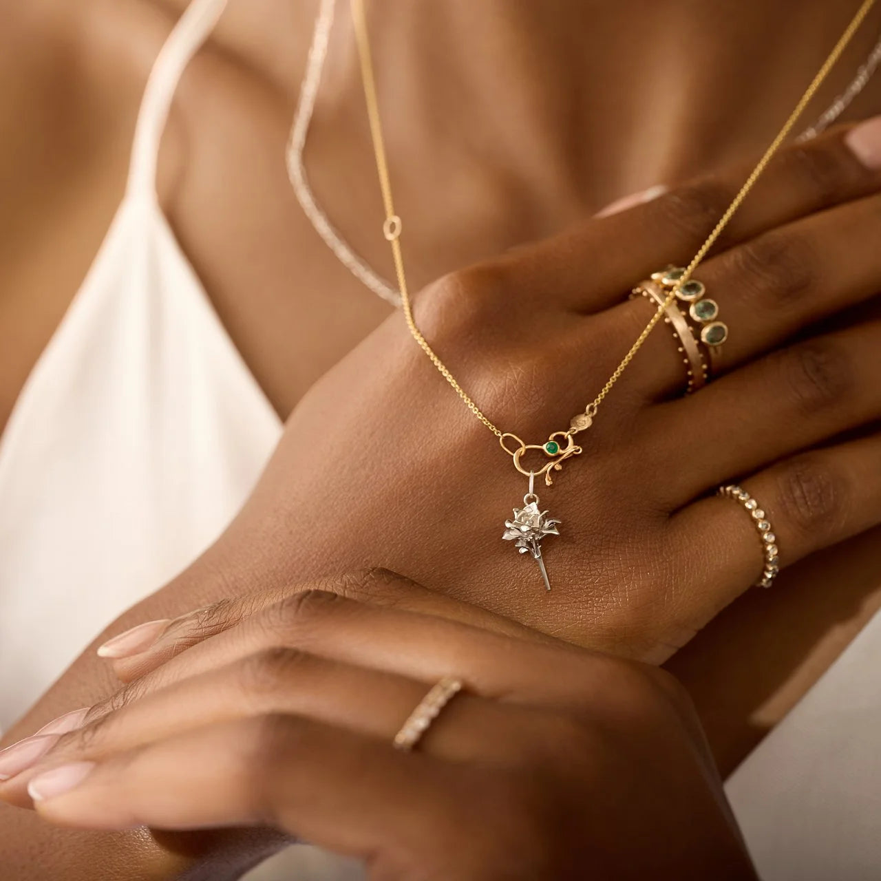 Close-up of a person's hand wearing gold jewelry with a necklace and rings.