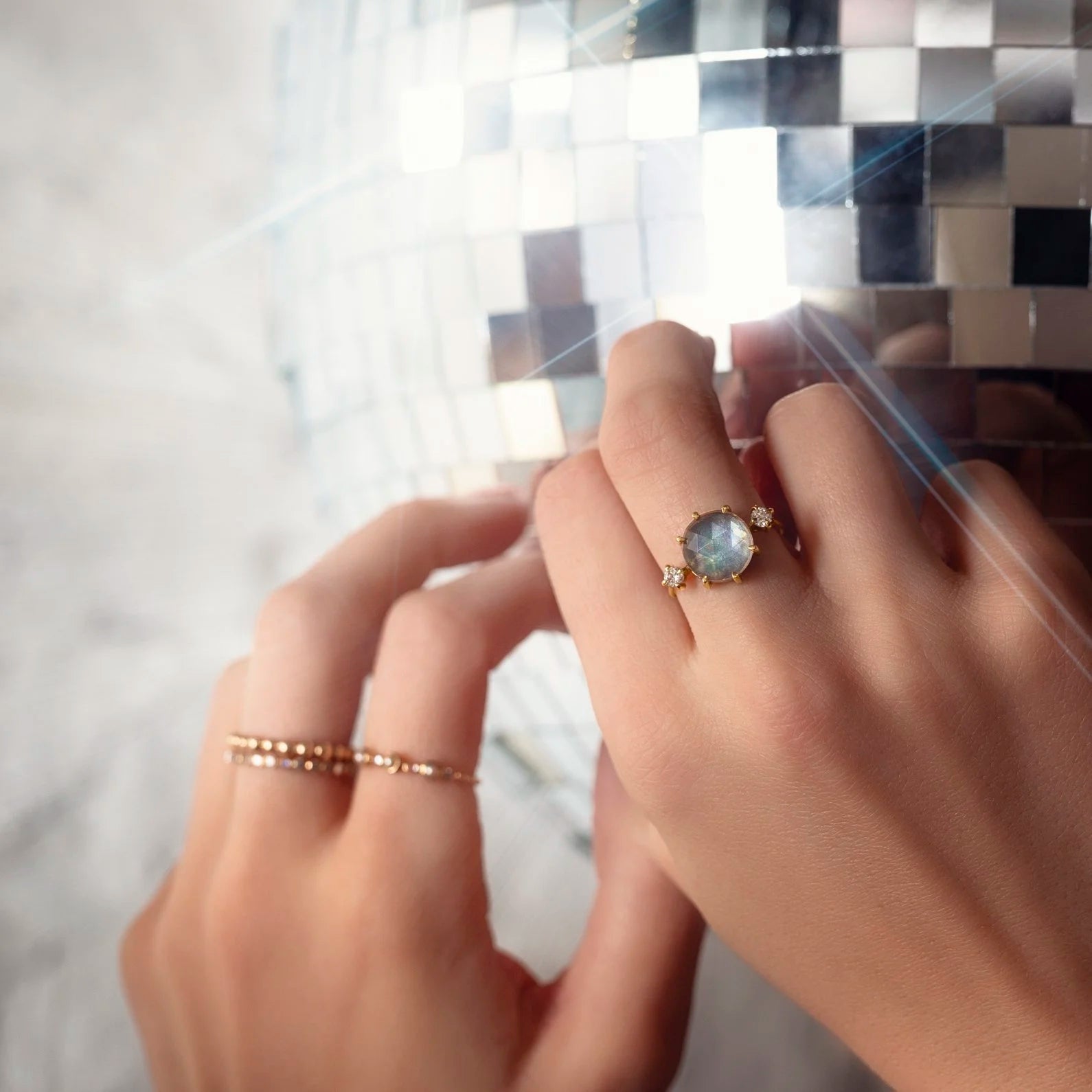 Close-up of a hand wearing a ring with a reflective surface in the background