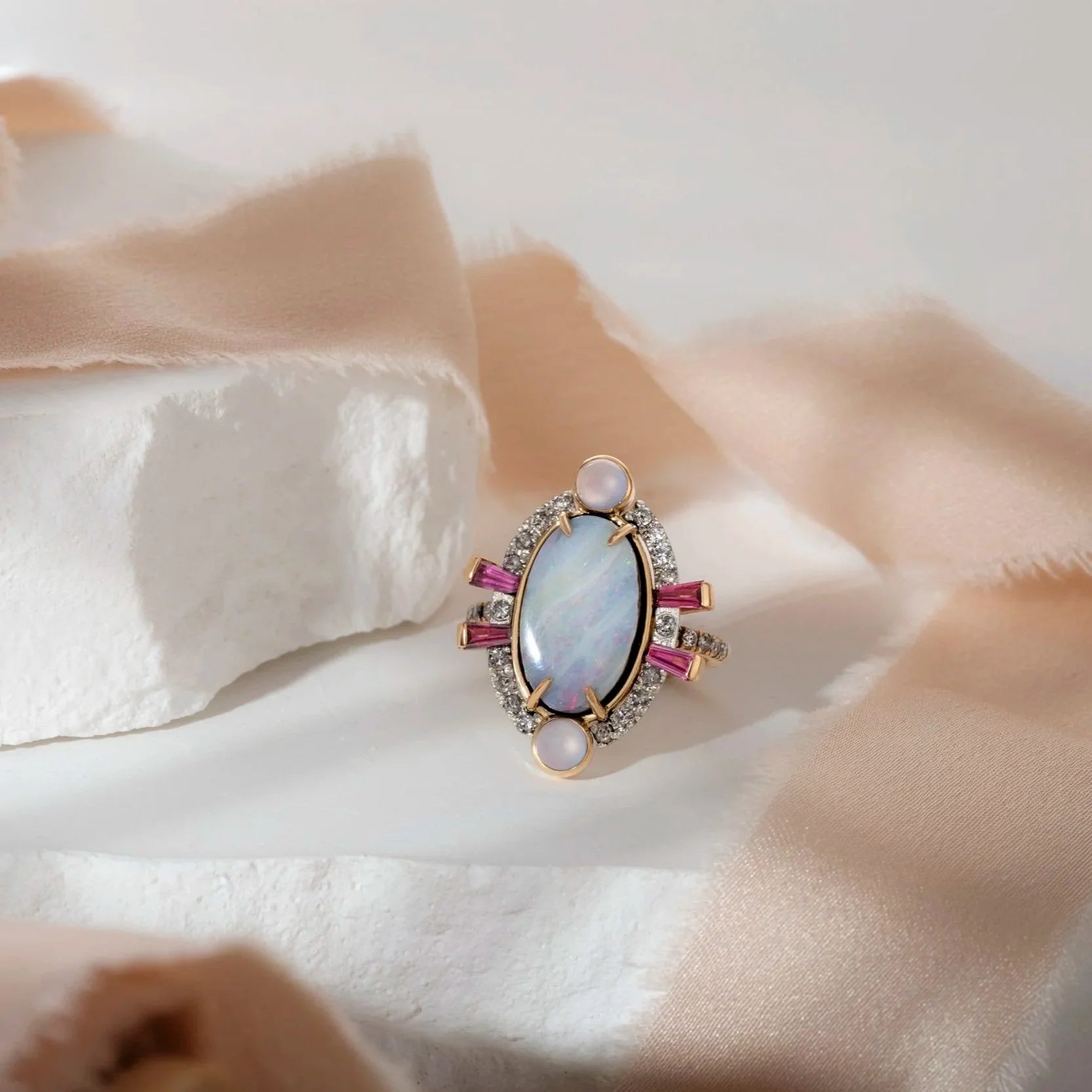 Elegant ring with a central gemstone and pink accents on a soft fabric background