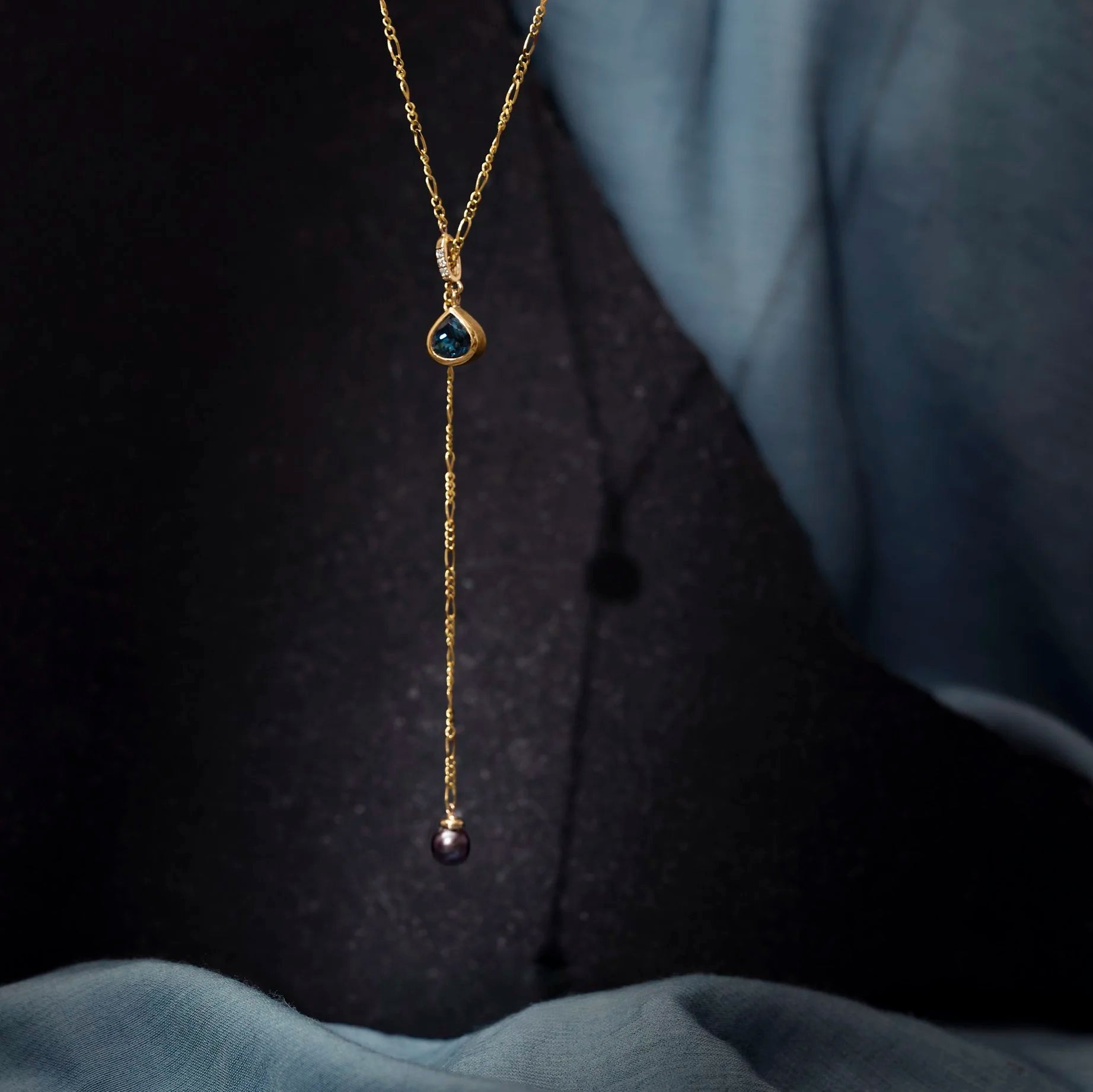 Gold necklace with a pendant on a dark fabric background