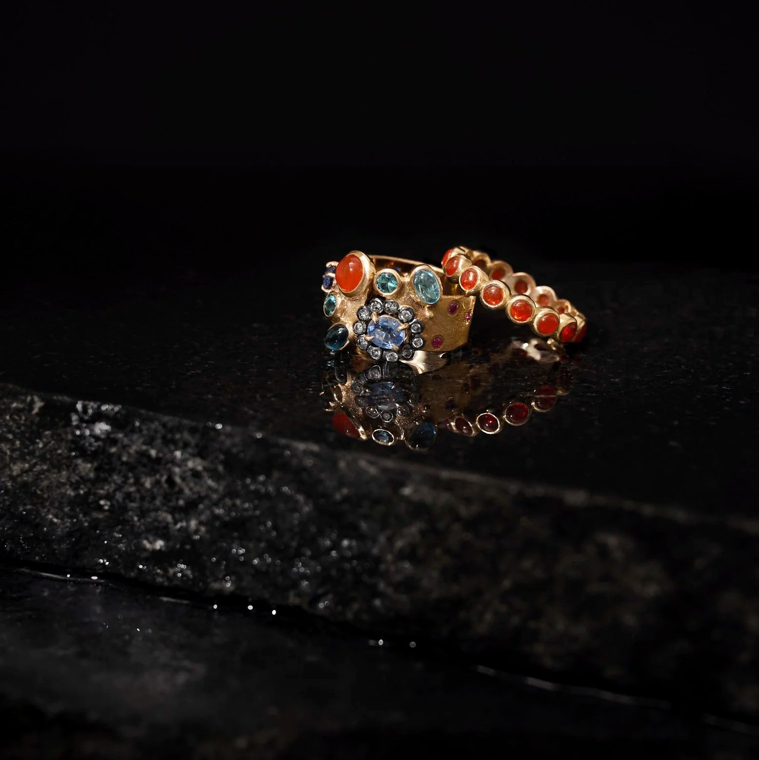 Gold ring with colorful gemstones on a dark surface