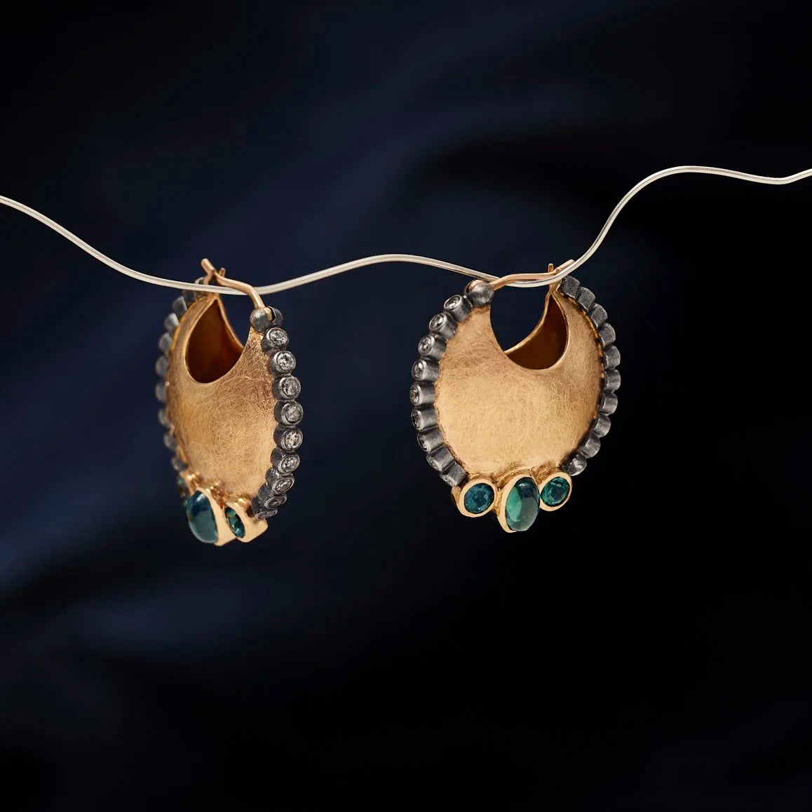 Gold earrings with gemstones on a dark background