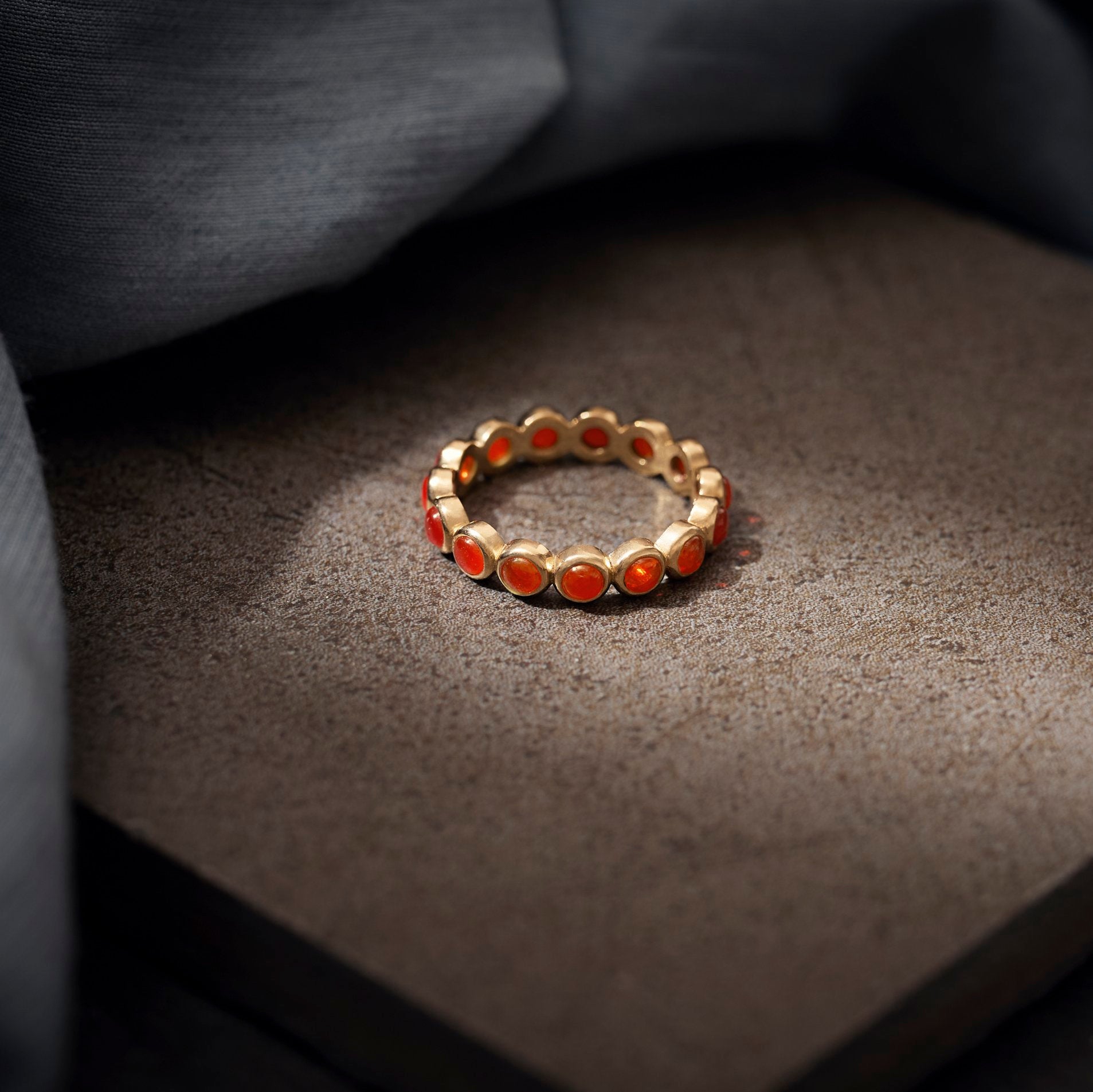 Gold ring with orange stones on a textured surface