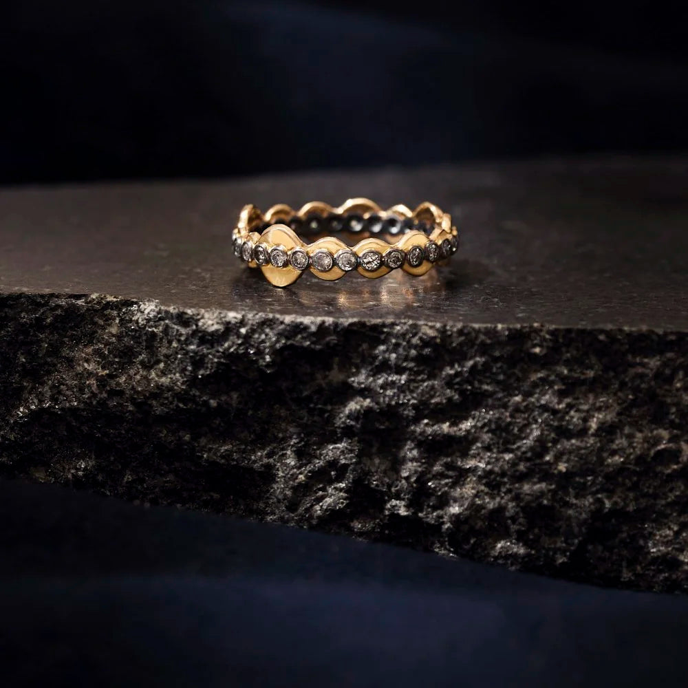 Gold ring with diamonds on a dark stone surface