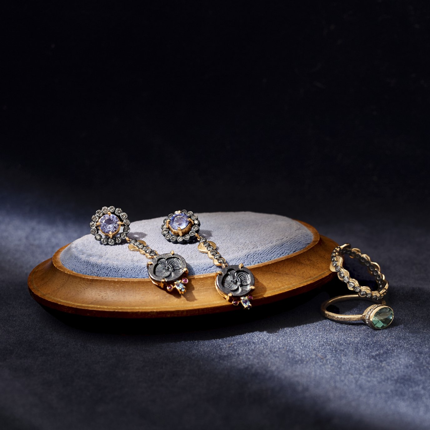 Pair of earrings with gemstones on a wooden stand against a dark background