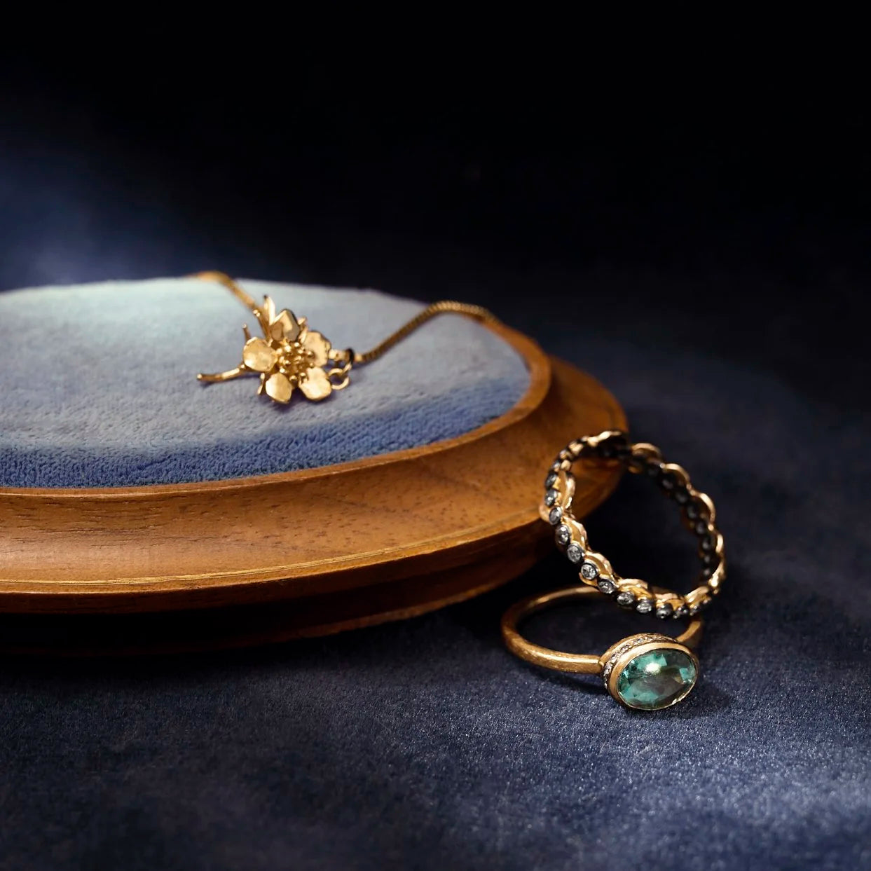 Gold necklace and ring on a blue and brown textured surface