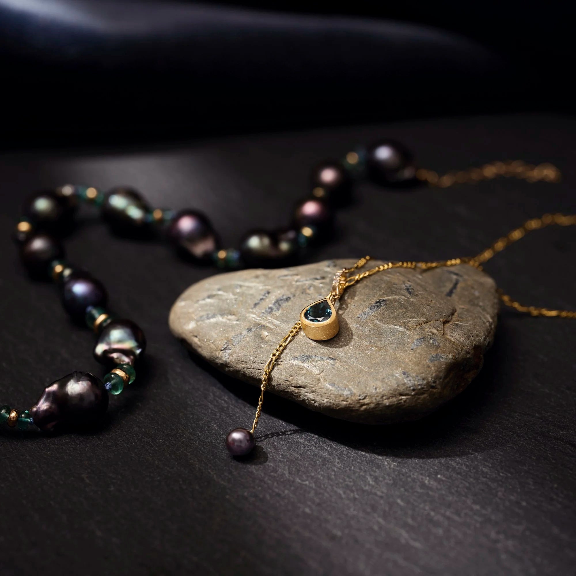 Pearl necklace and pendant on a dark stone surface