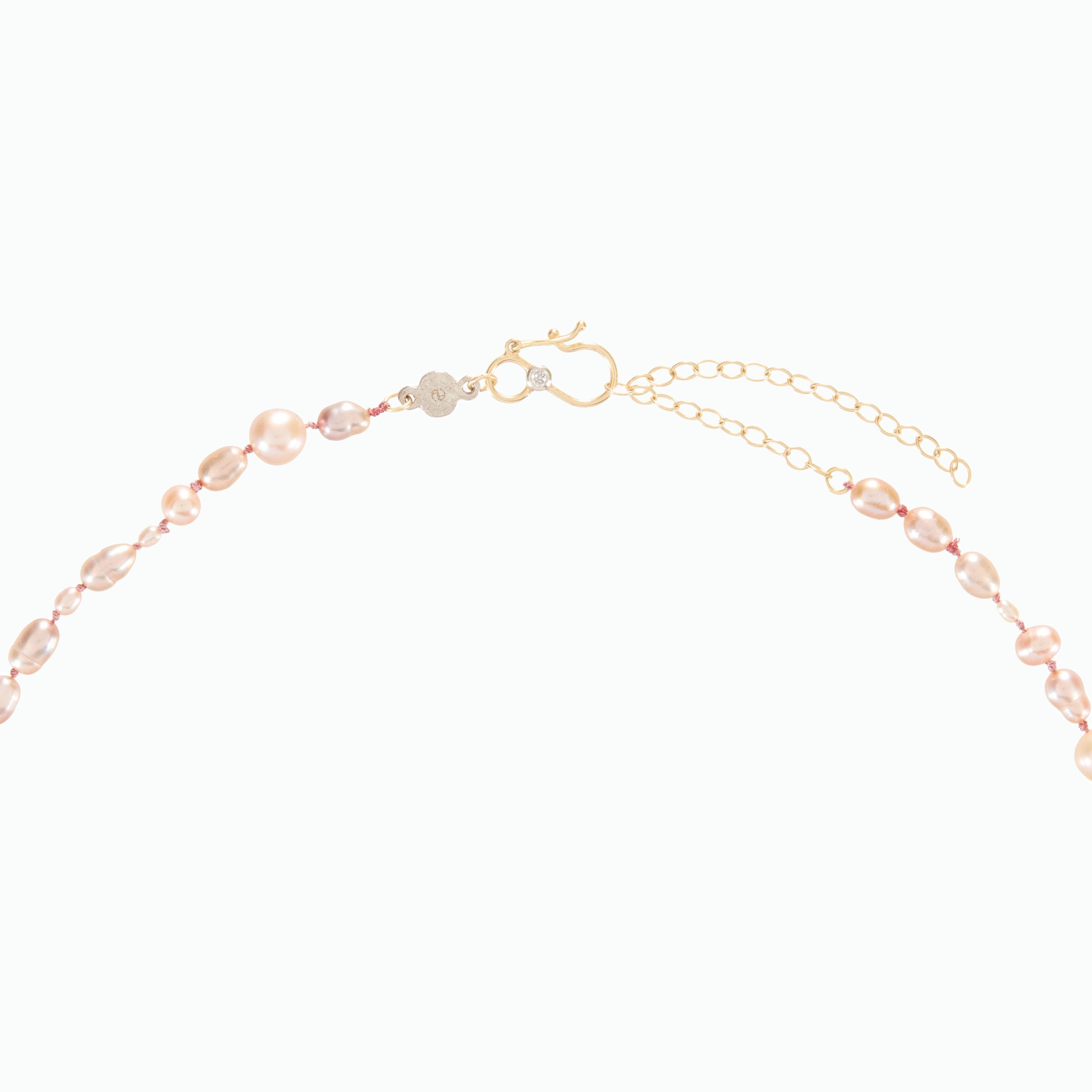 Gold bracelet with pink beads on a white background