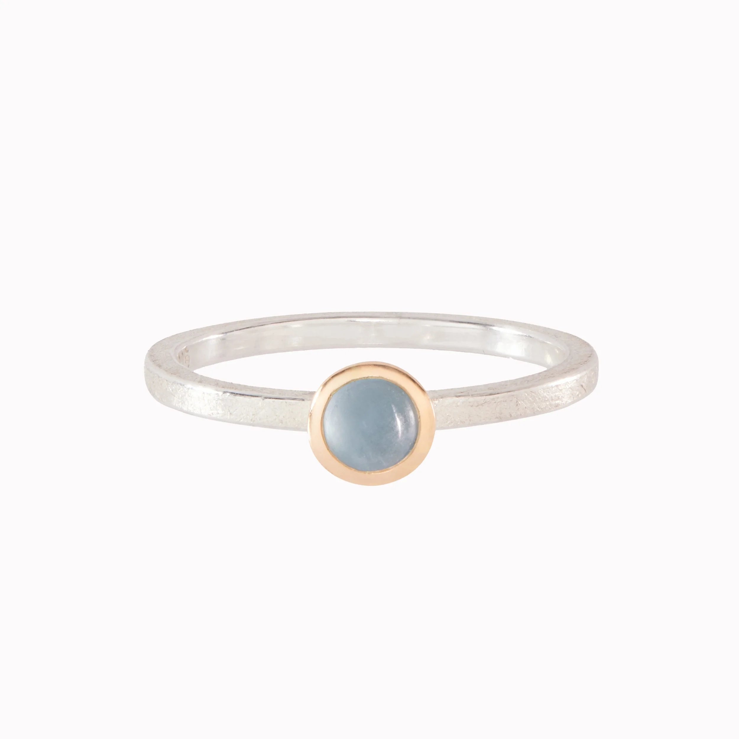 Silver and gold ring with light blue gemstone on a white background