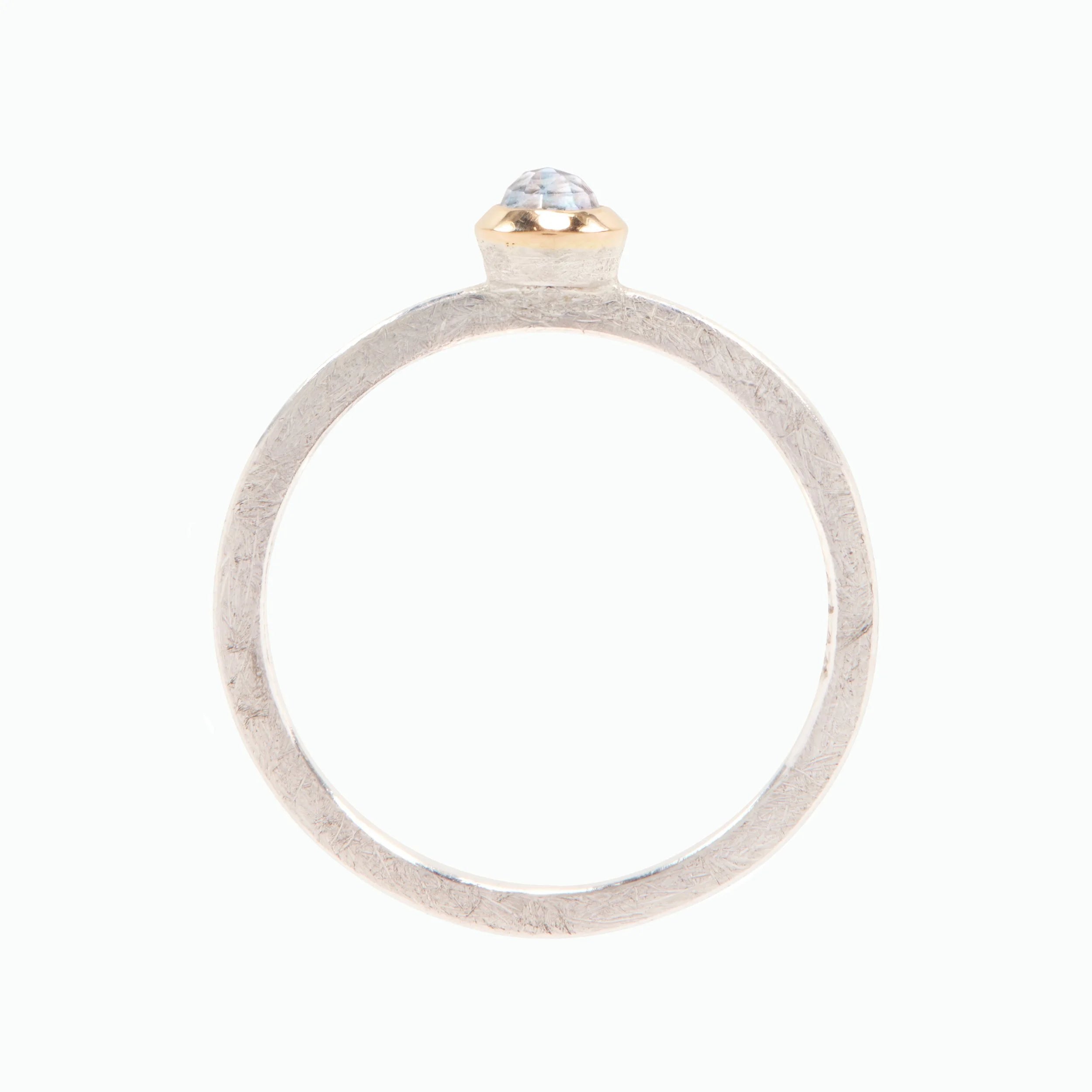Silver ring with a gold and moonstone top on a white background