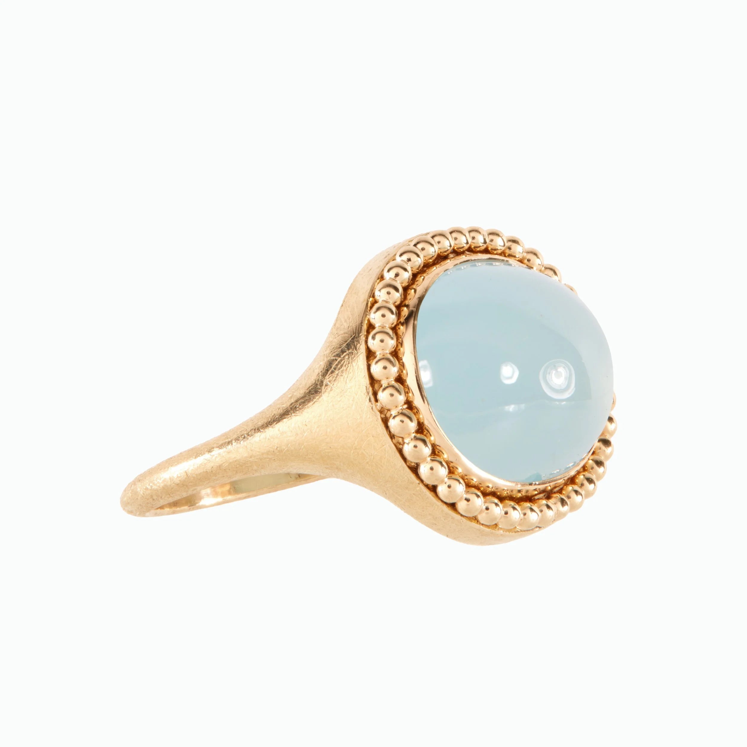 Gold ring with a light blue gemstone on a white background