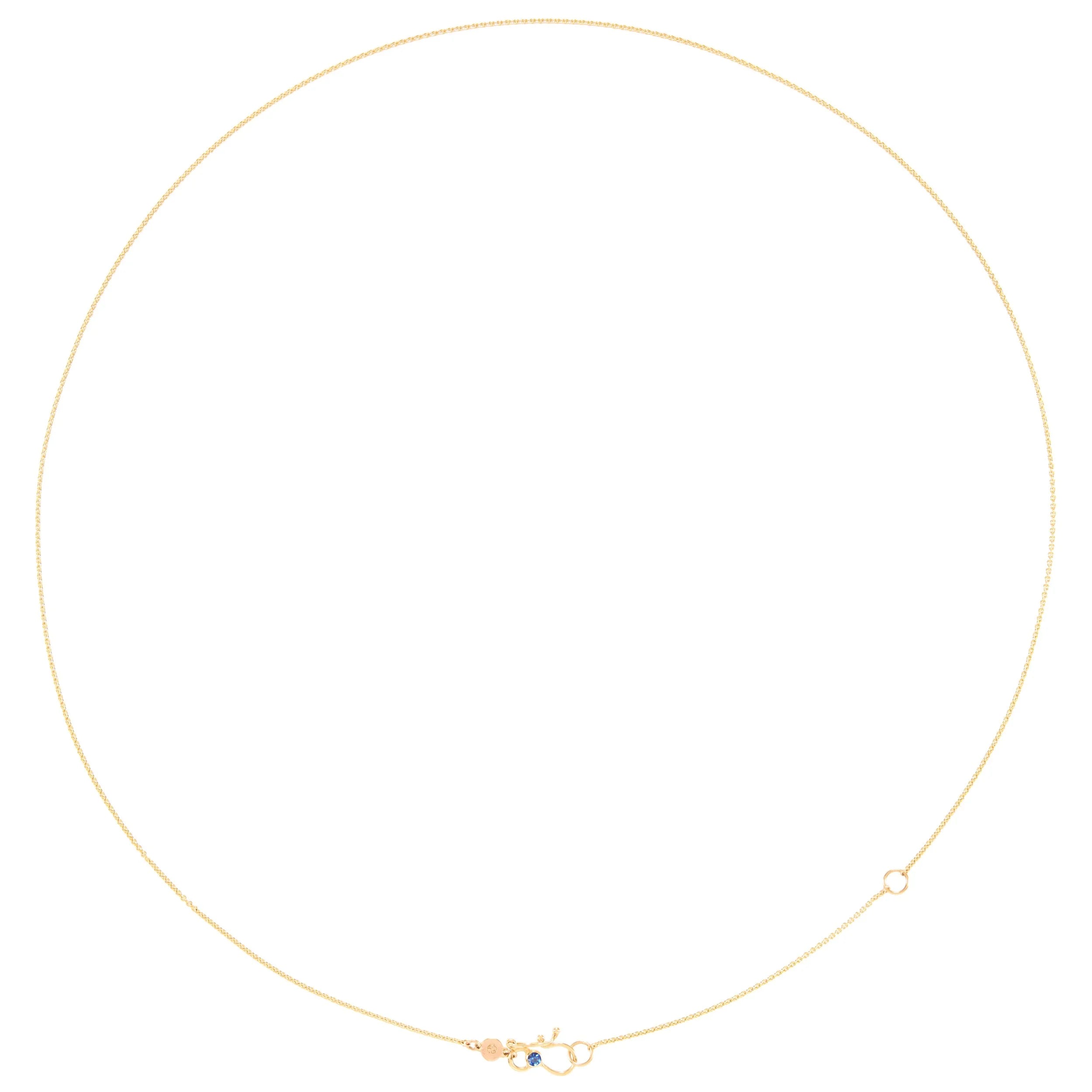 Gold necklace with a small blue gemstone on a white background