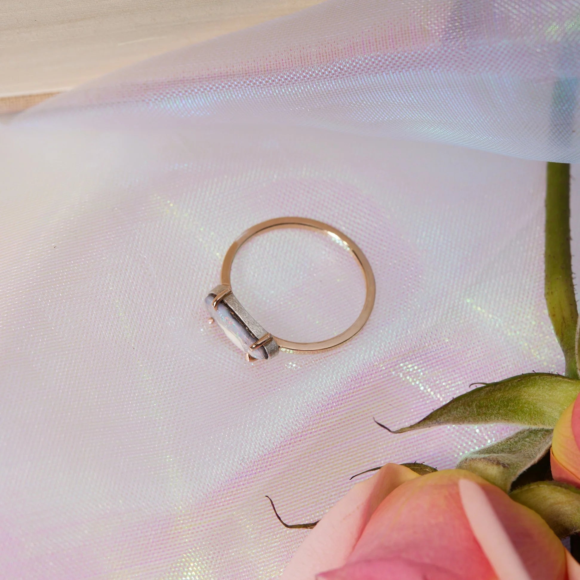 Gold ring on a textured fabric surface with a pink flower.