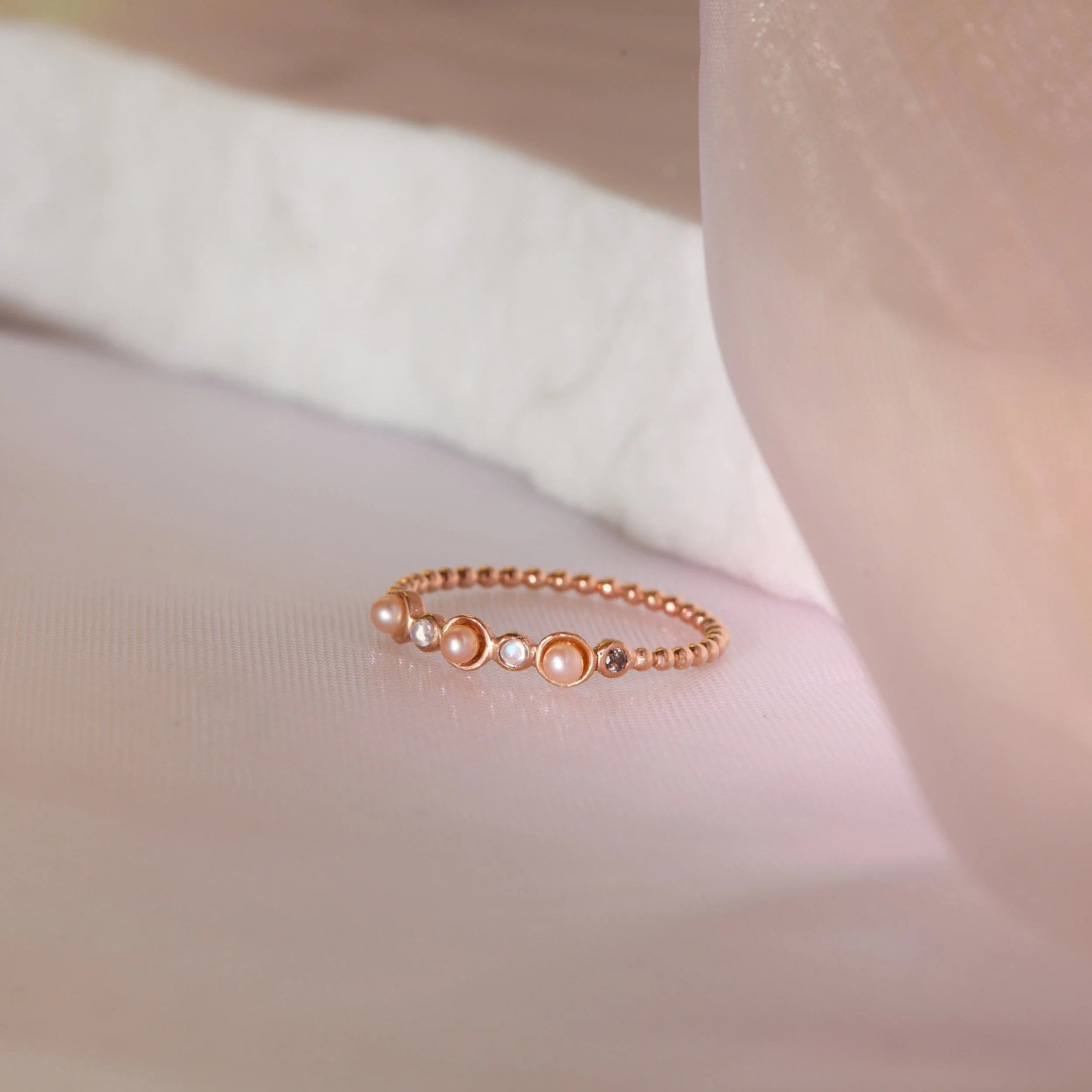 Gold ring with embedded stones on a soft fabric background