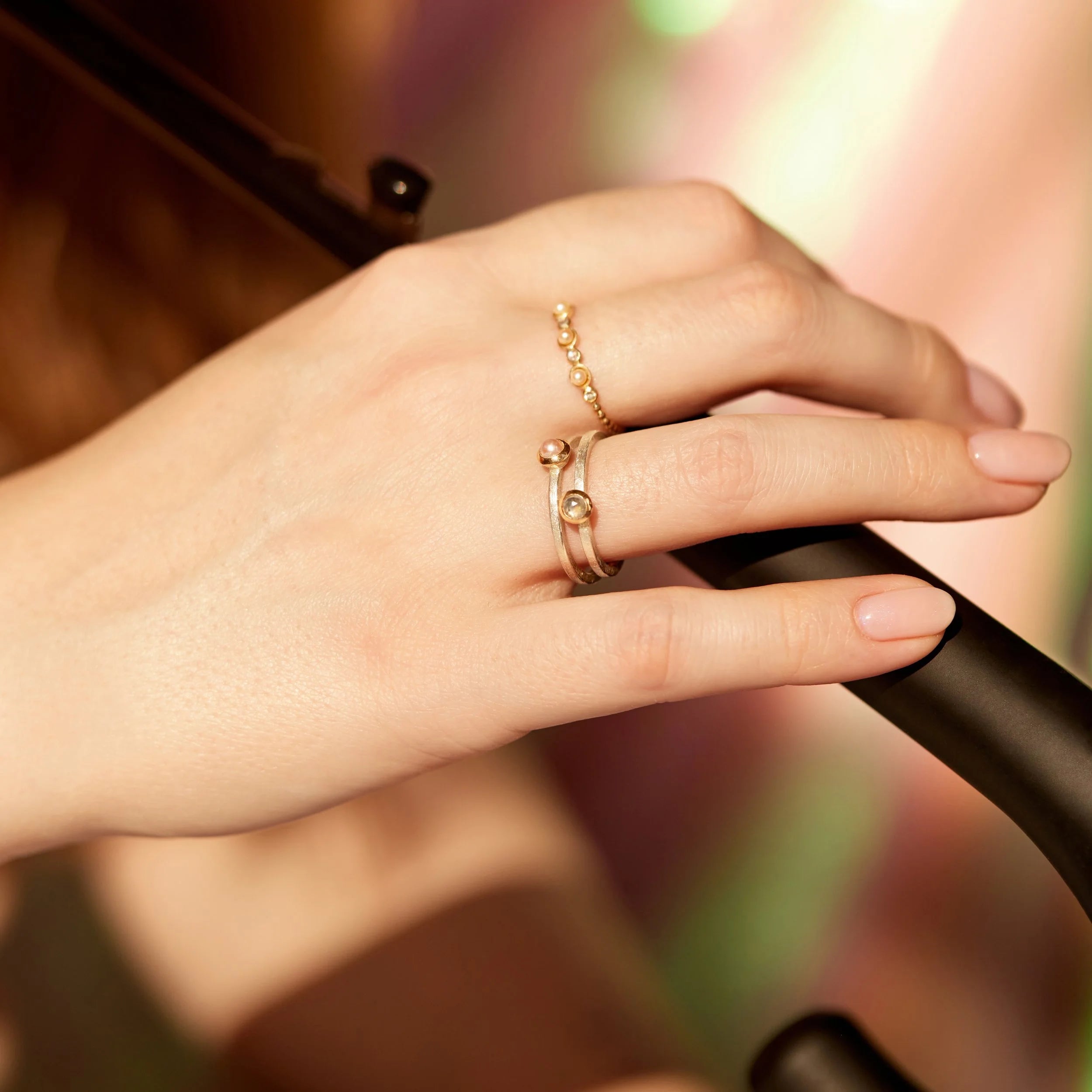 Hand wearing a gold ring on a blurred background