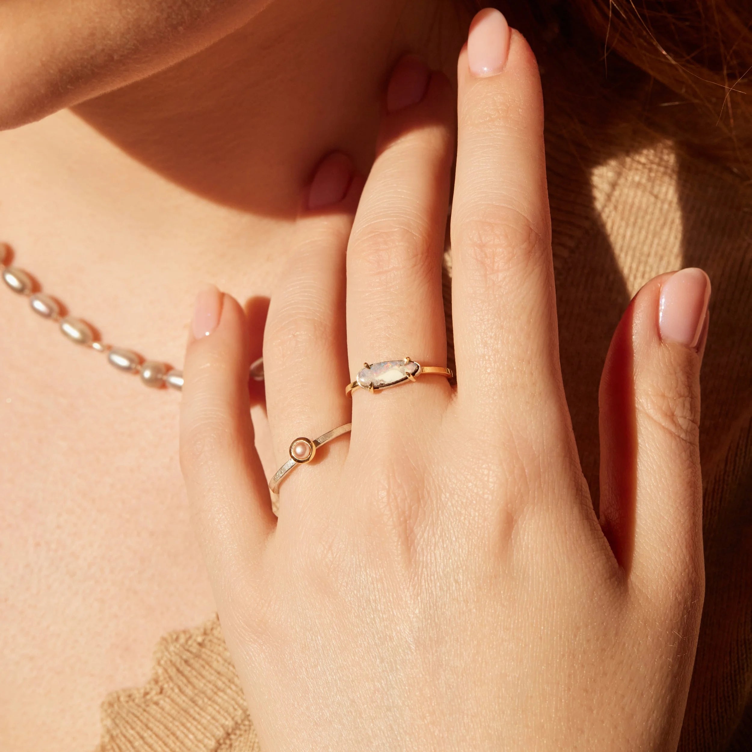 Close-up of a hand wearing two gold rings with a soft focus background