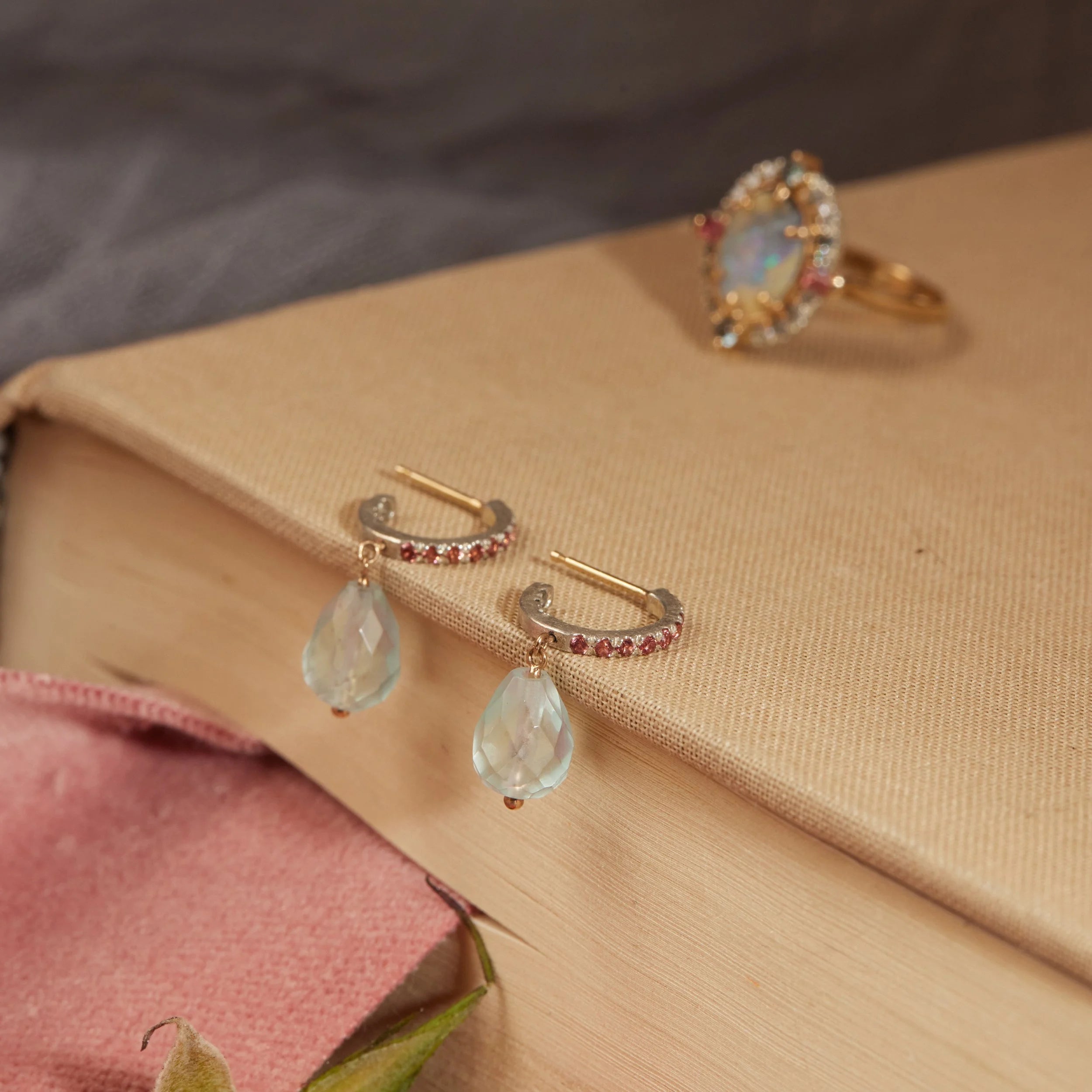 Pair of gemstone hoops dangling off edge of tan book.