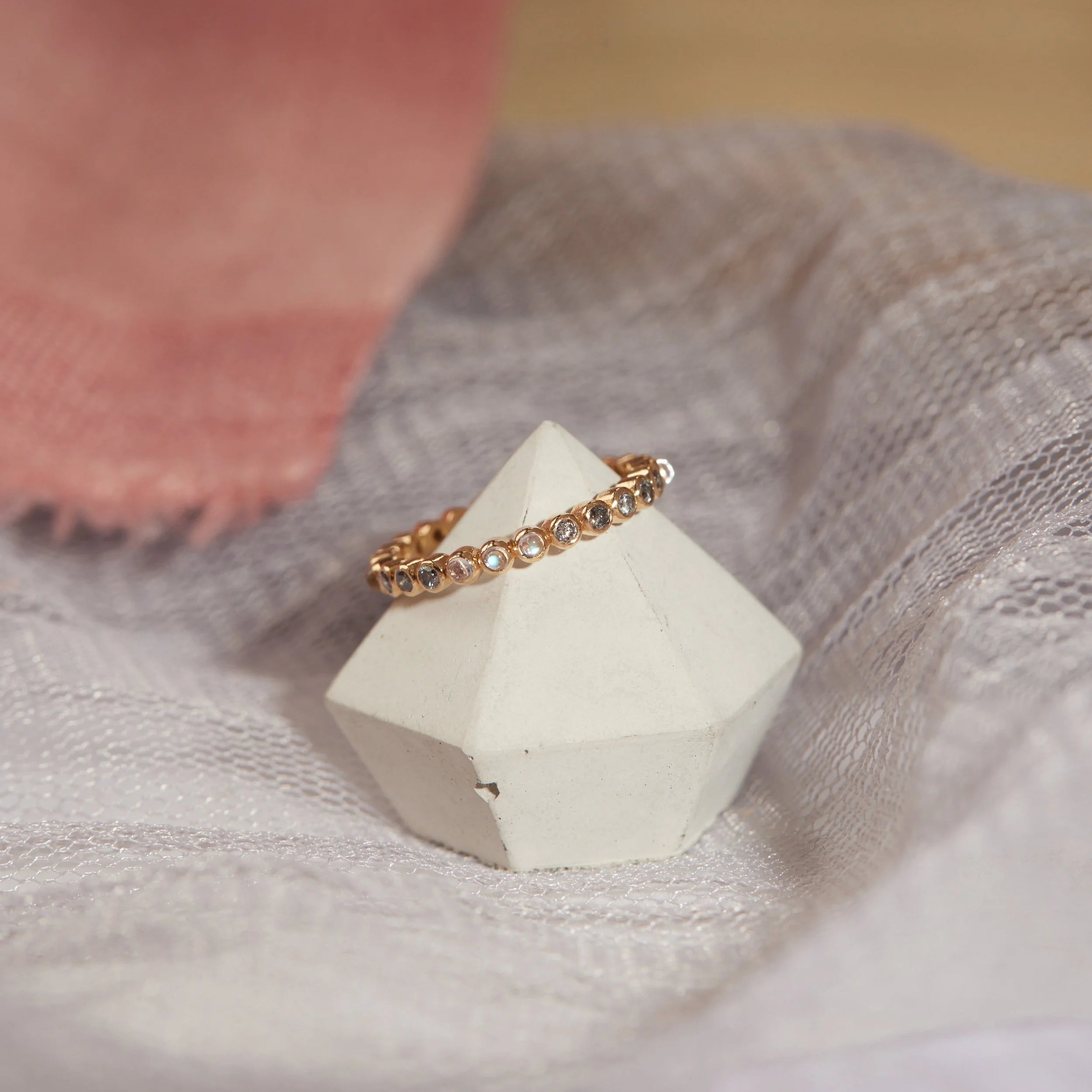 Gold ring with small stones on a white geometric stone