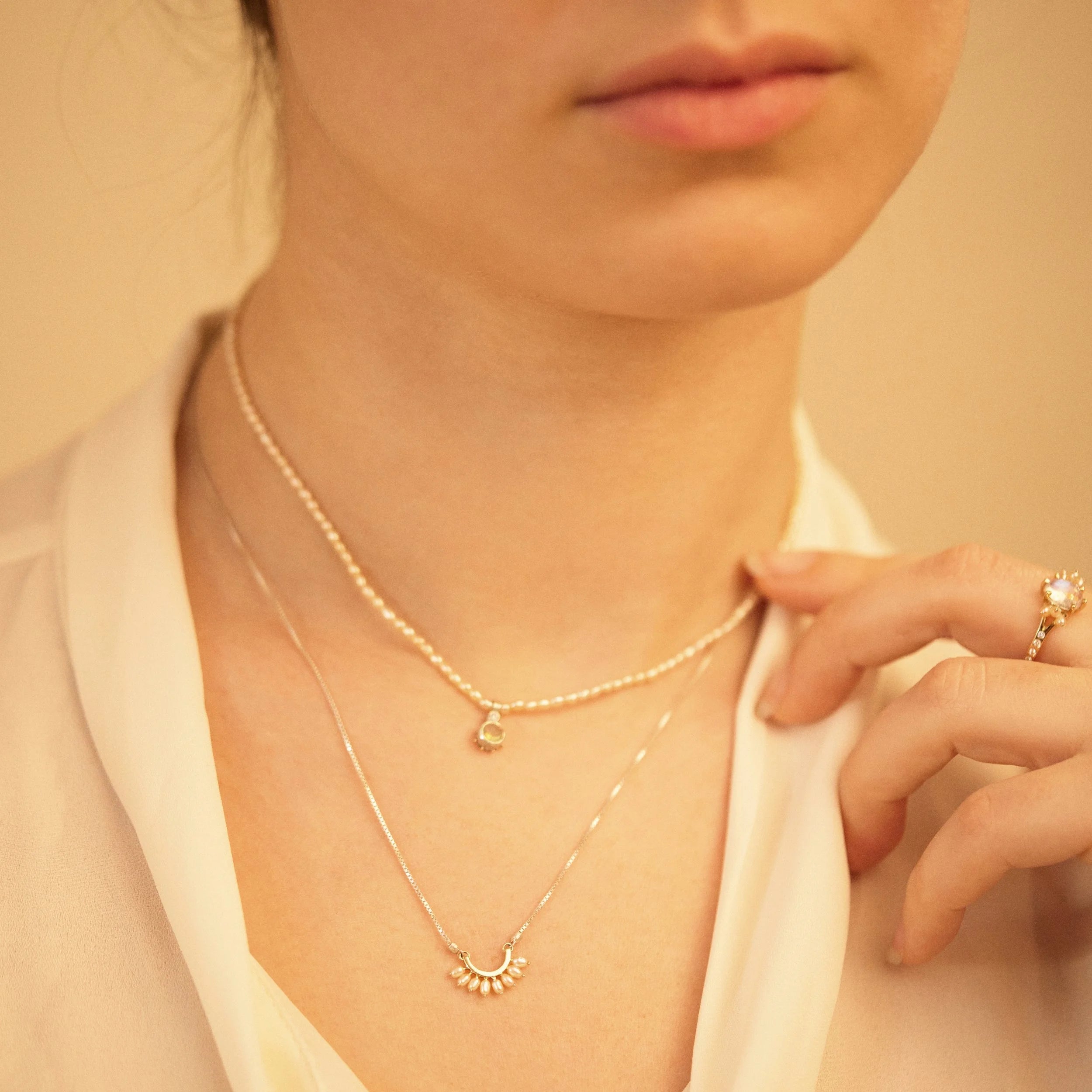 Close-up of a person wearing two necklaces with a soft background