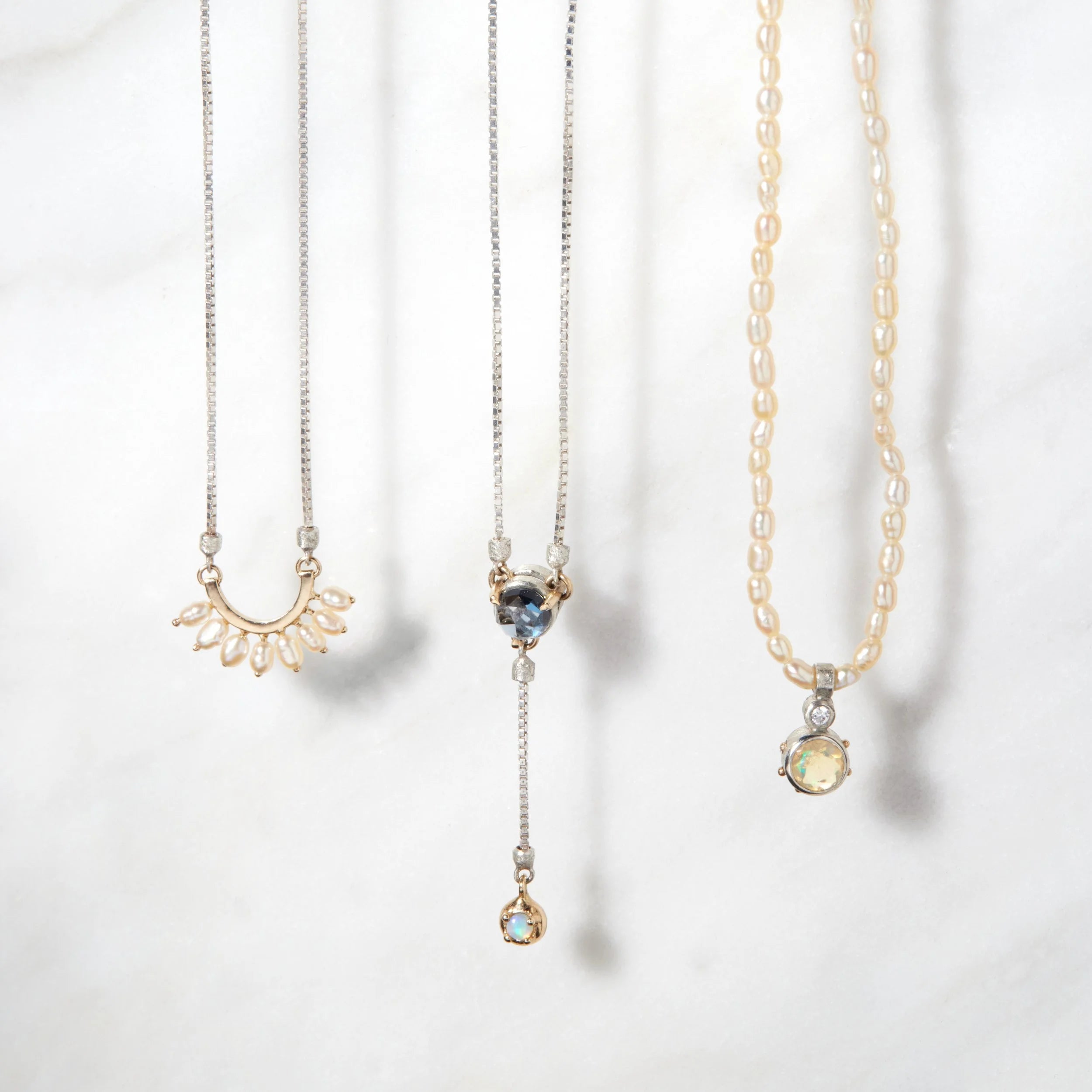 Three gold necklaces with various pendants on a white background
