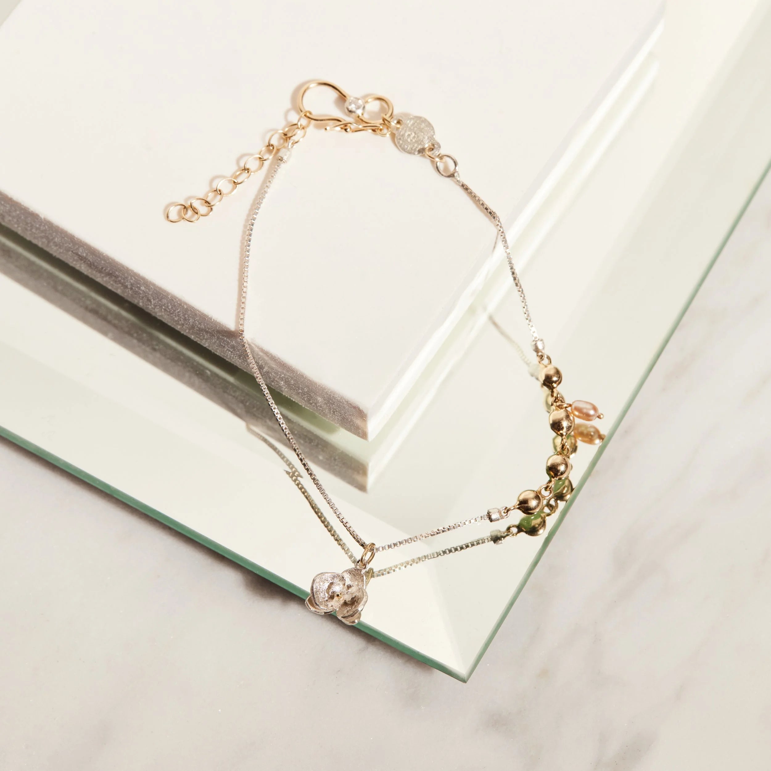 Silver bracelet with gold beads on a reflective surface