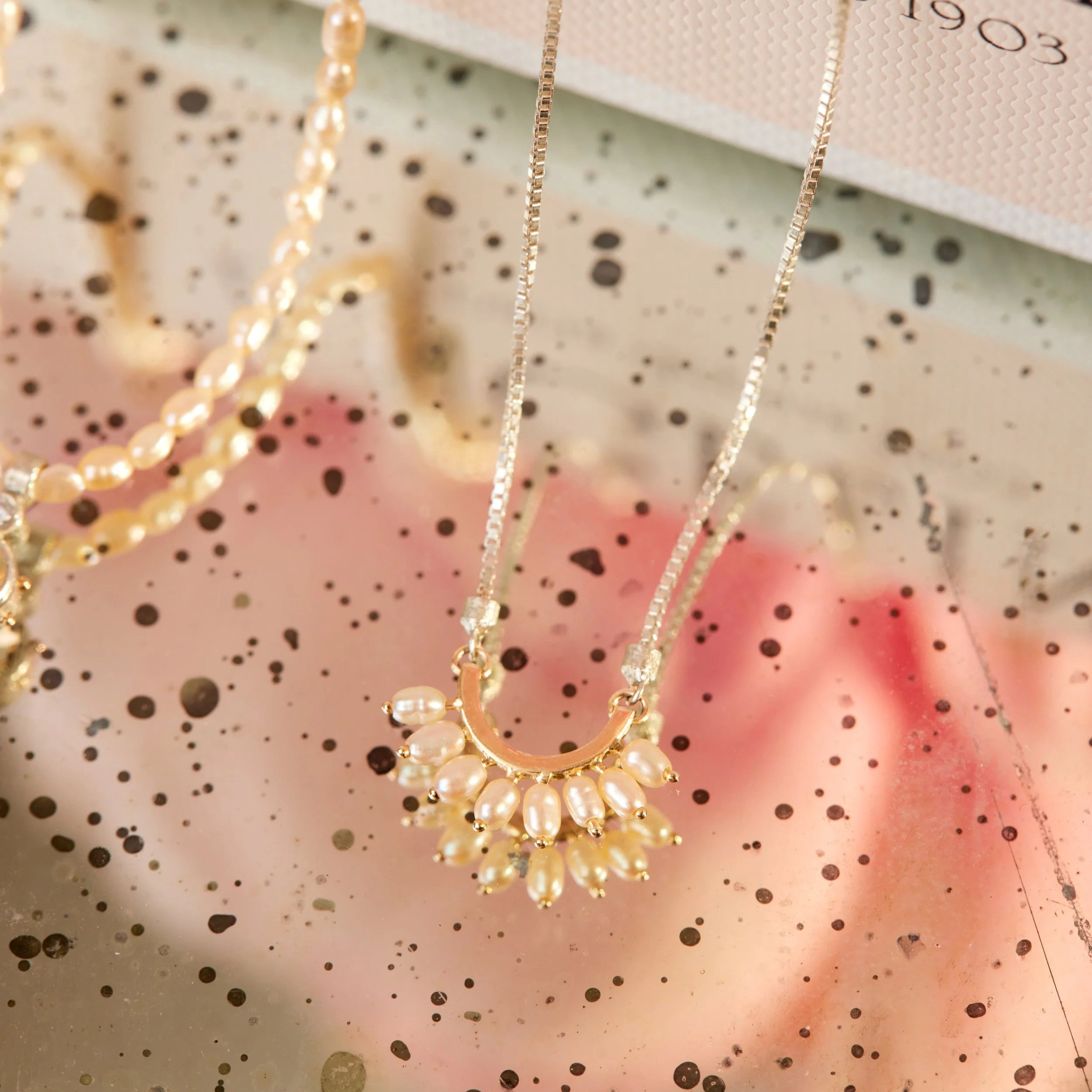 Gold necklace with a pearl pendant on a decorative background