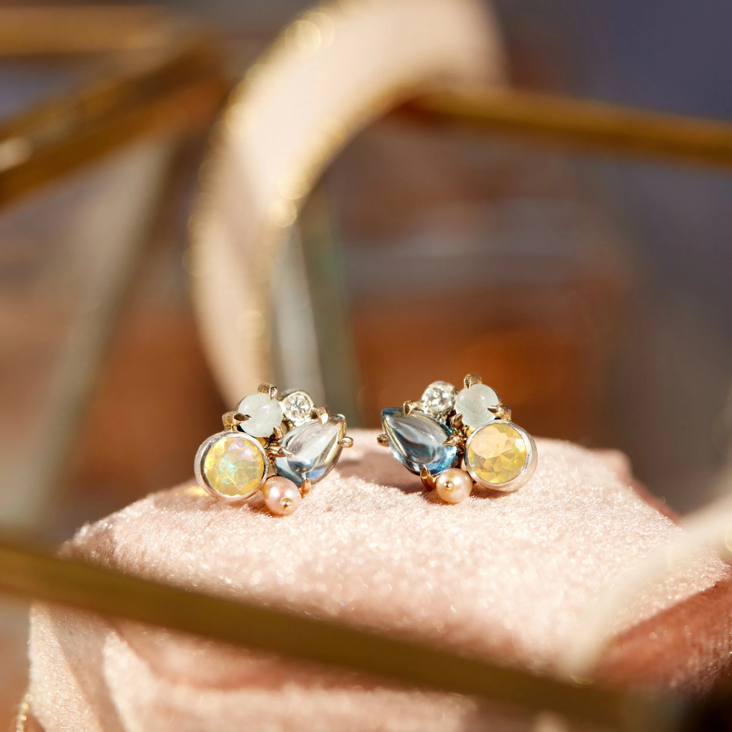 Pair of earrings with multicolored gemstones on a pink cushion