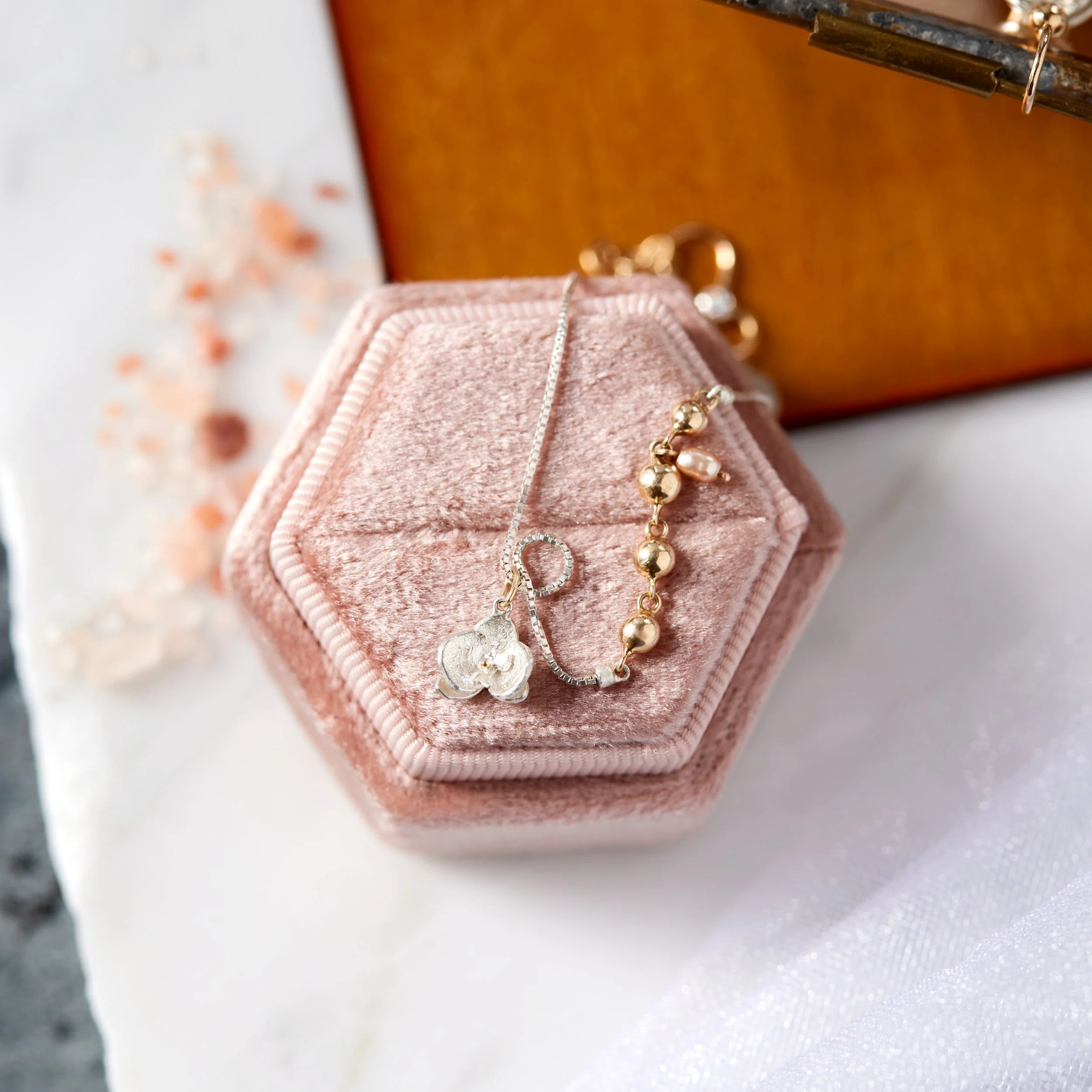 Hexagonal pink velvet jewelry box with a bracelet on a white surface