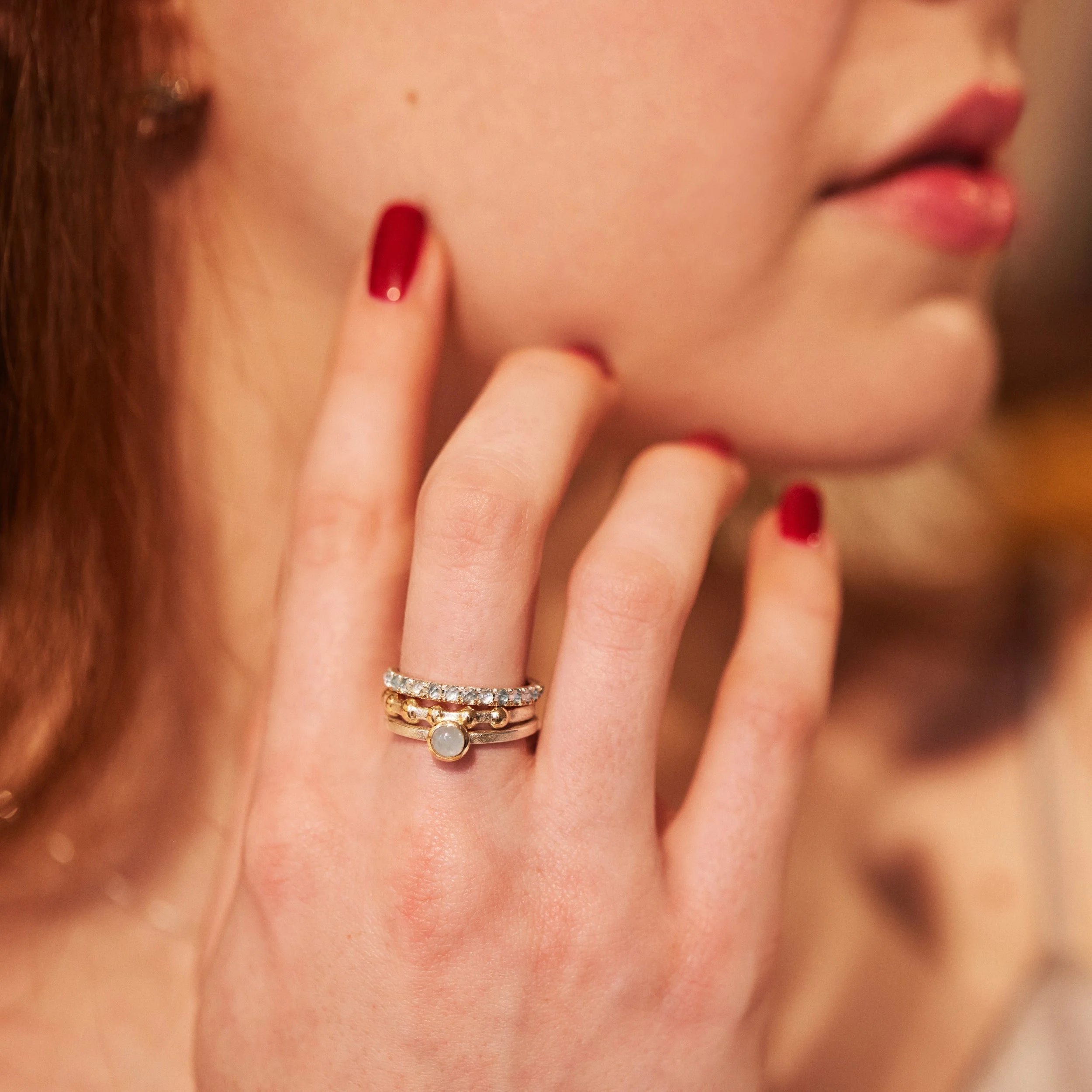 Close-up of a hand wearing three rings with a blurred background