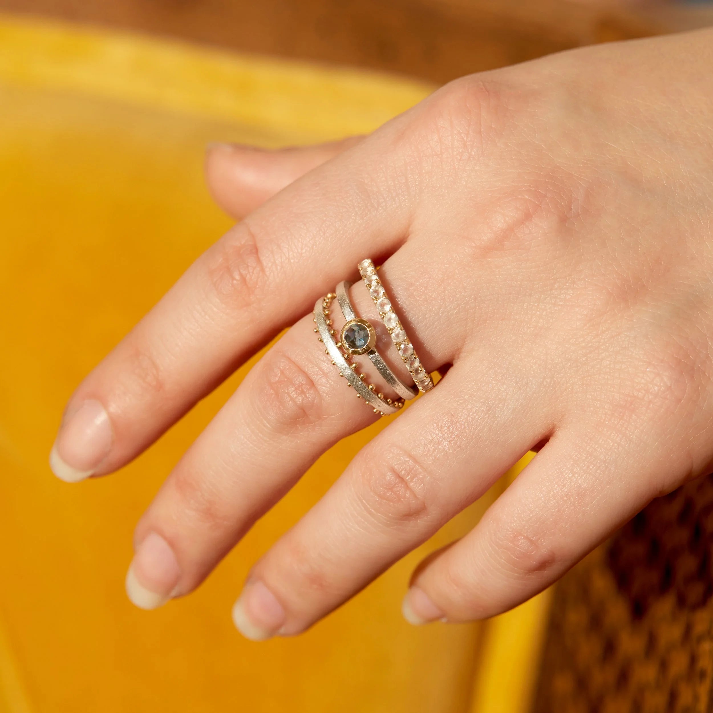 Hand wearing a stack of rings on a blurred background