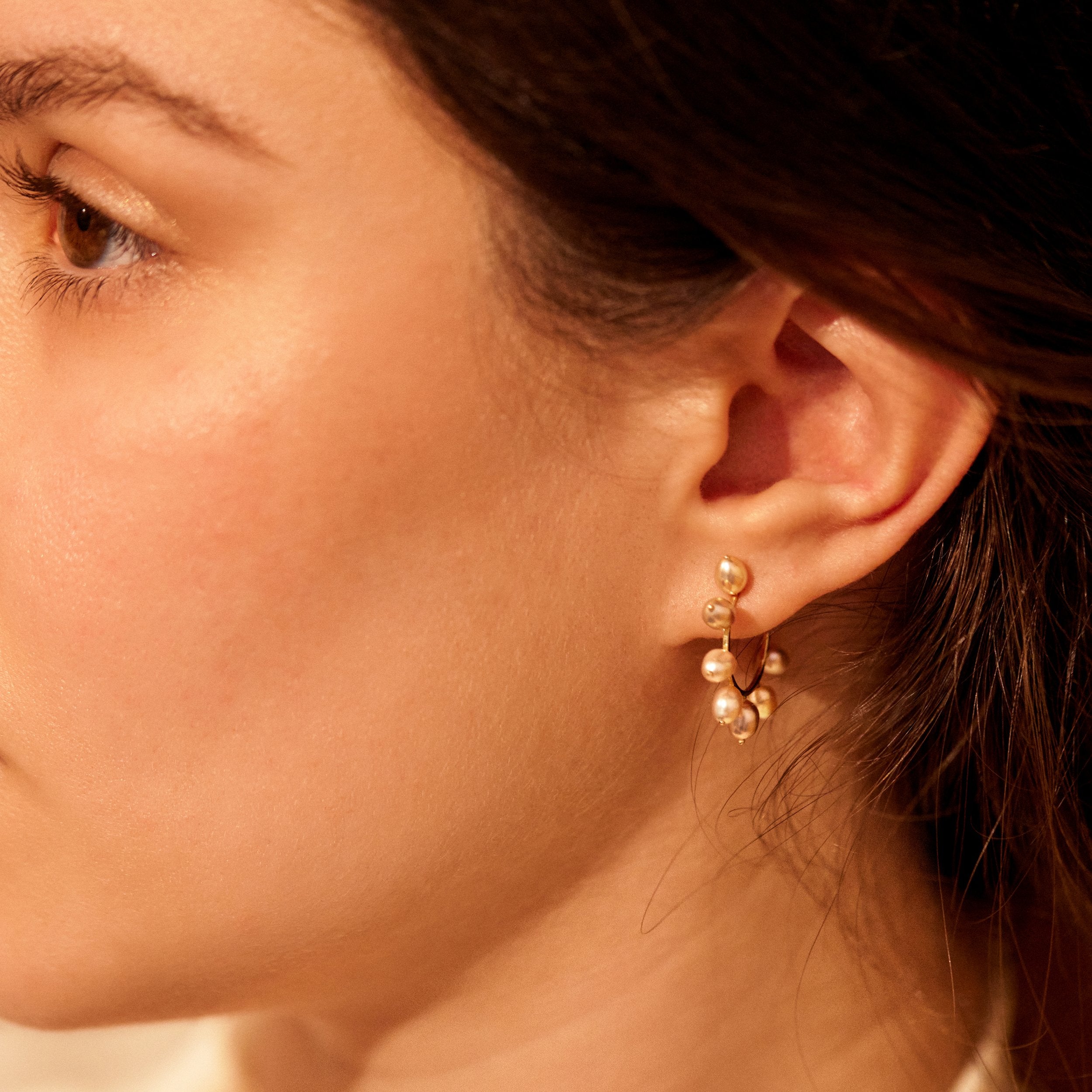 Close-up of a woman wearing gold earrings with a blurred background