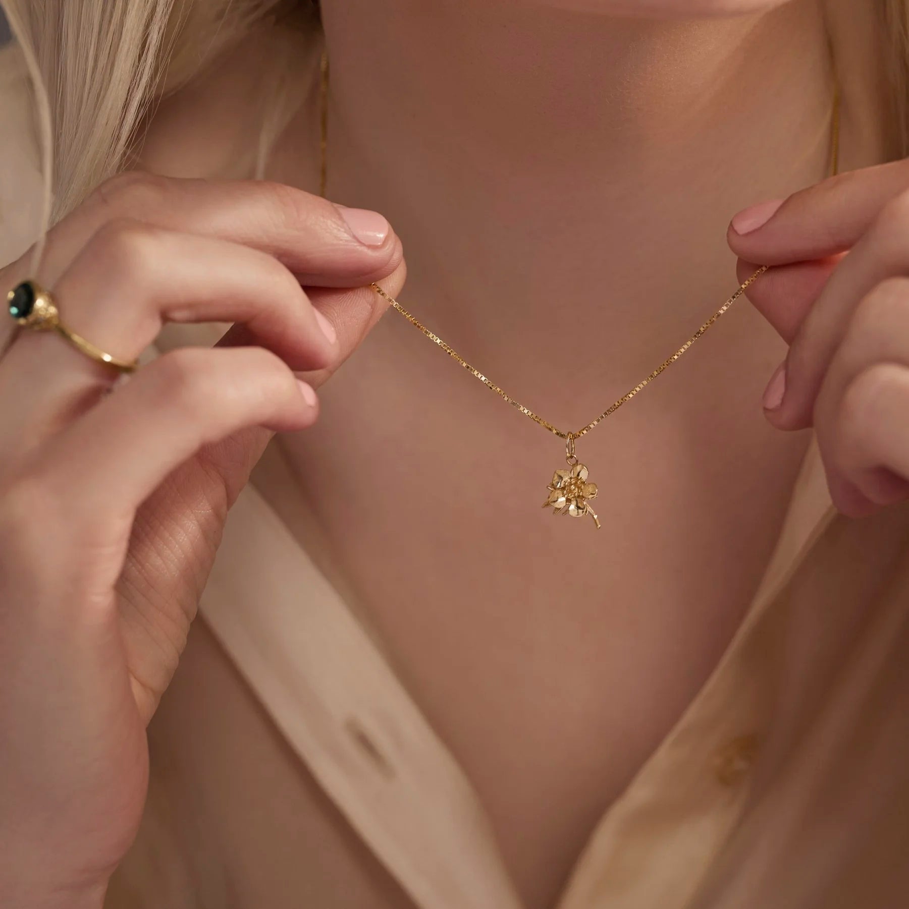 Close-up of a person wearing a gold necklace with a pendant.