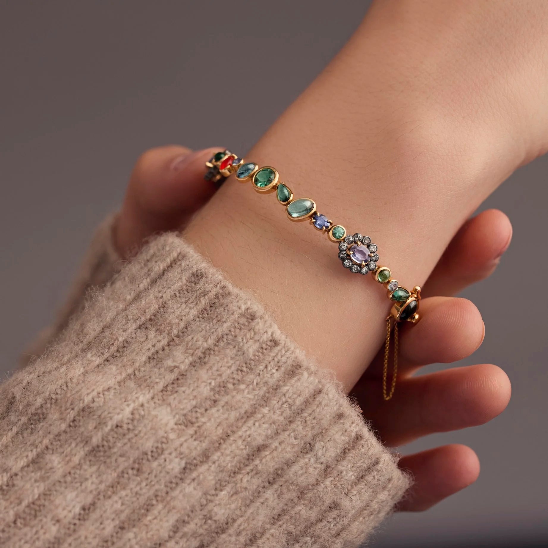 Bracelet with colorful gemstones on a wrist against a neutral background