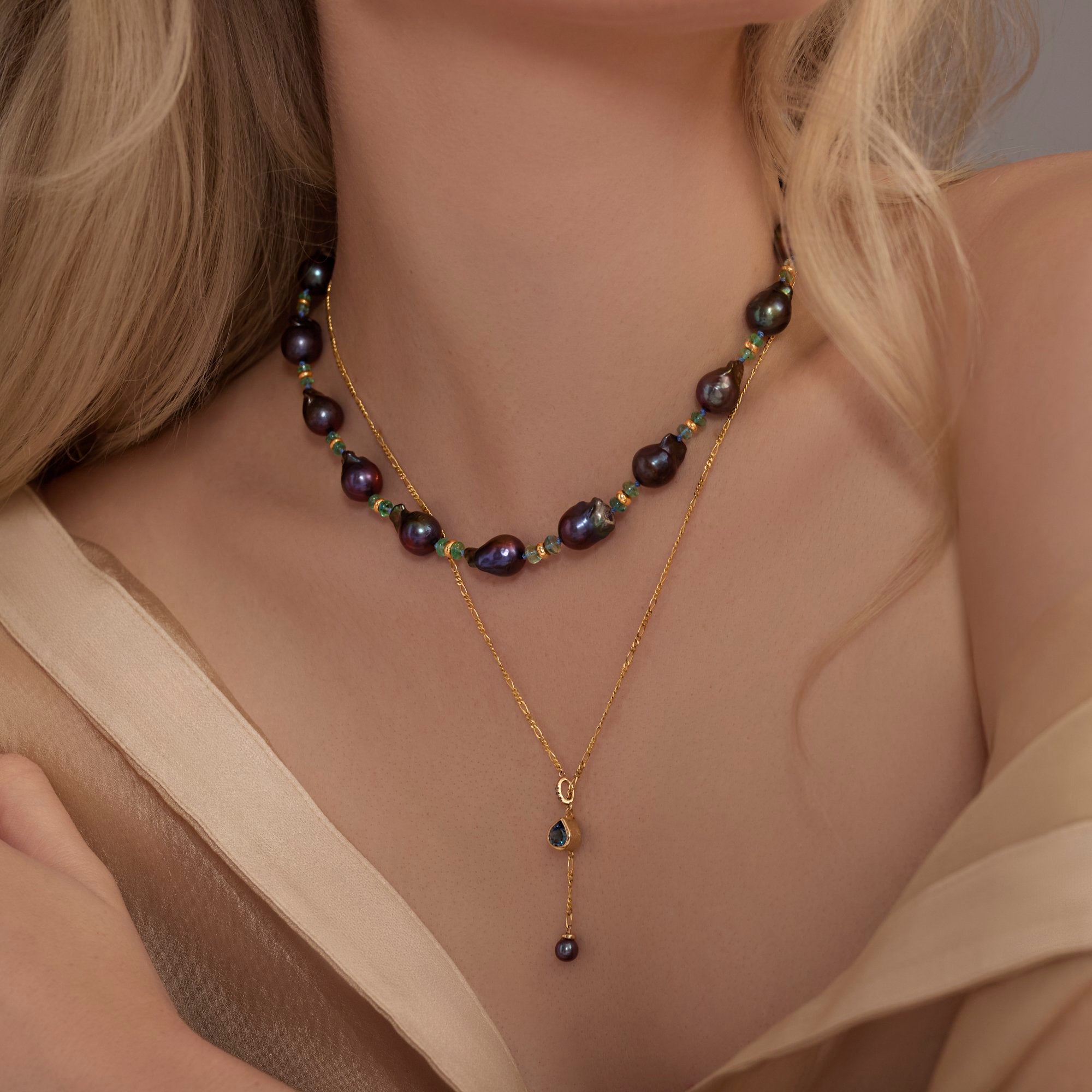 Gold necklace with black pearls worn by a model