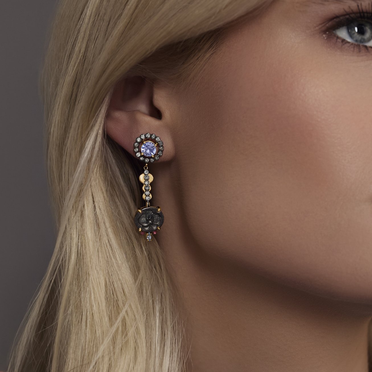 Close-up of a woman wearing a decorative earring with a gray background