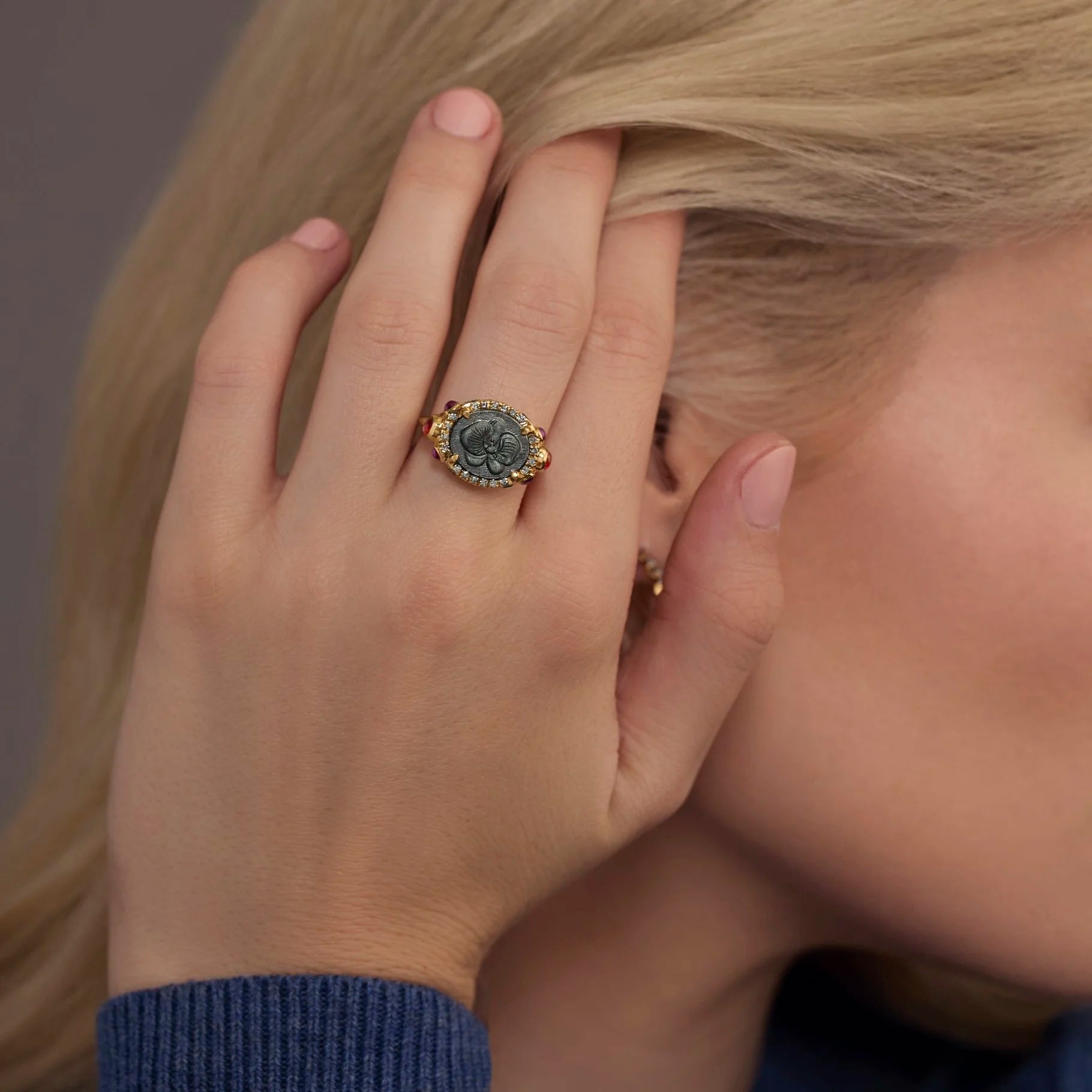 Close-up of a hand wearing a decorative ring with a blurred background