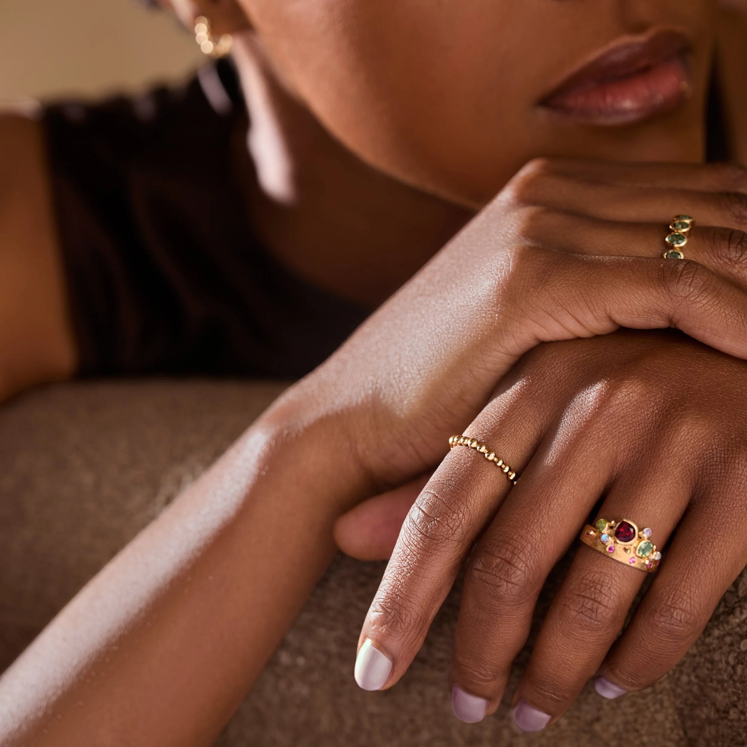 Close-up of a person's hand wearing multiple rings with a soft focus background