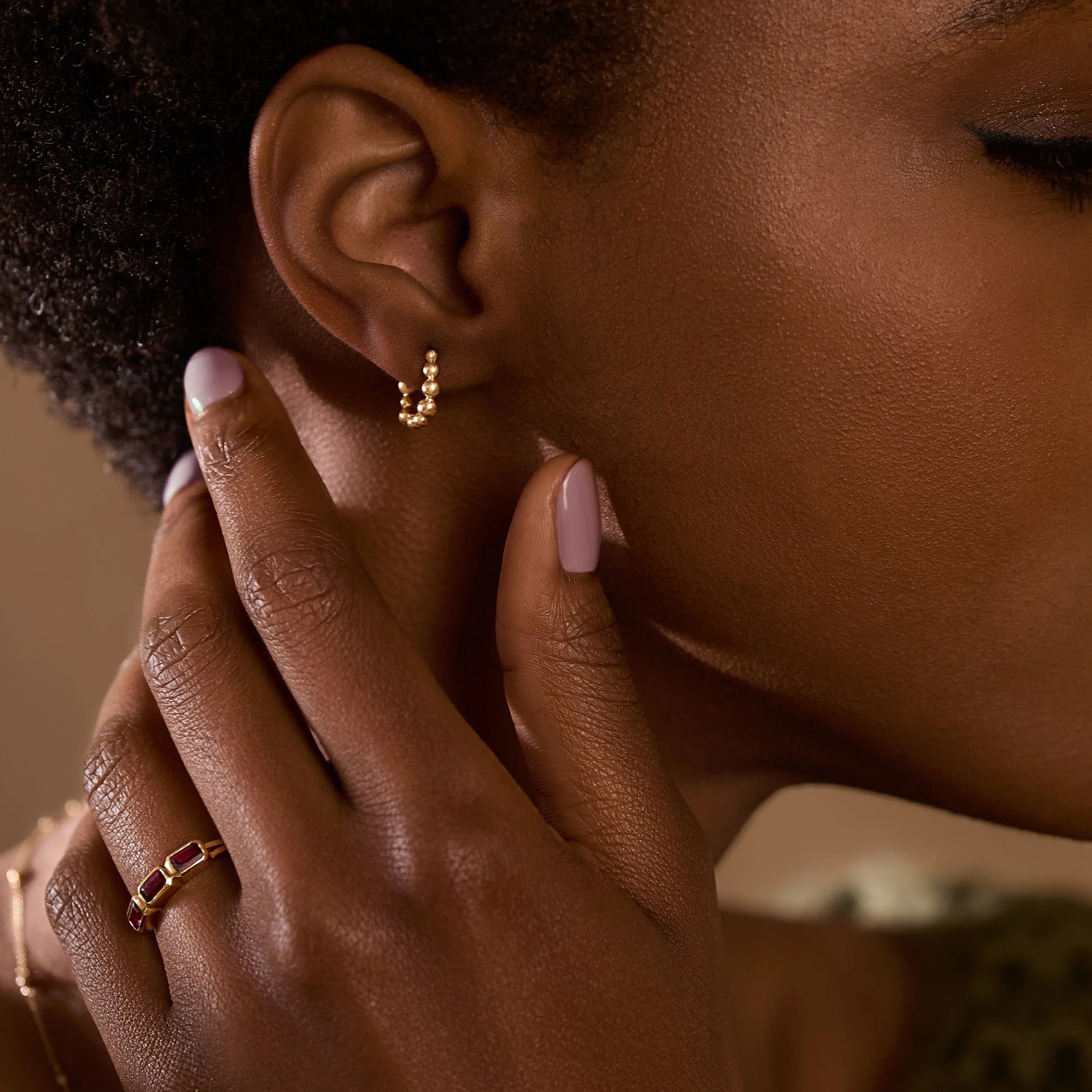 Close-up of a woman wearing gold hoop earrings with a blurred background
