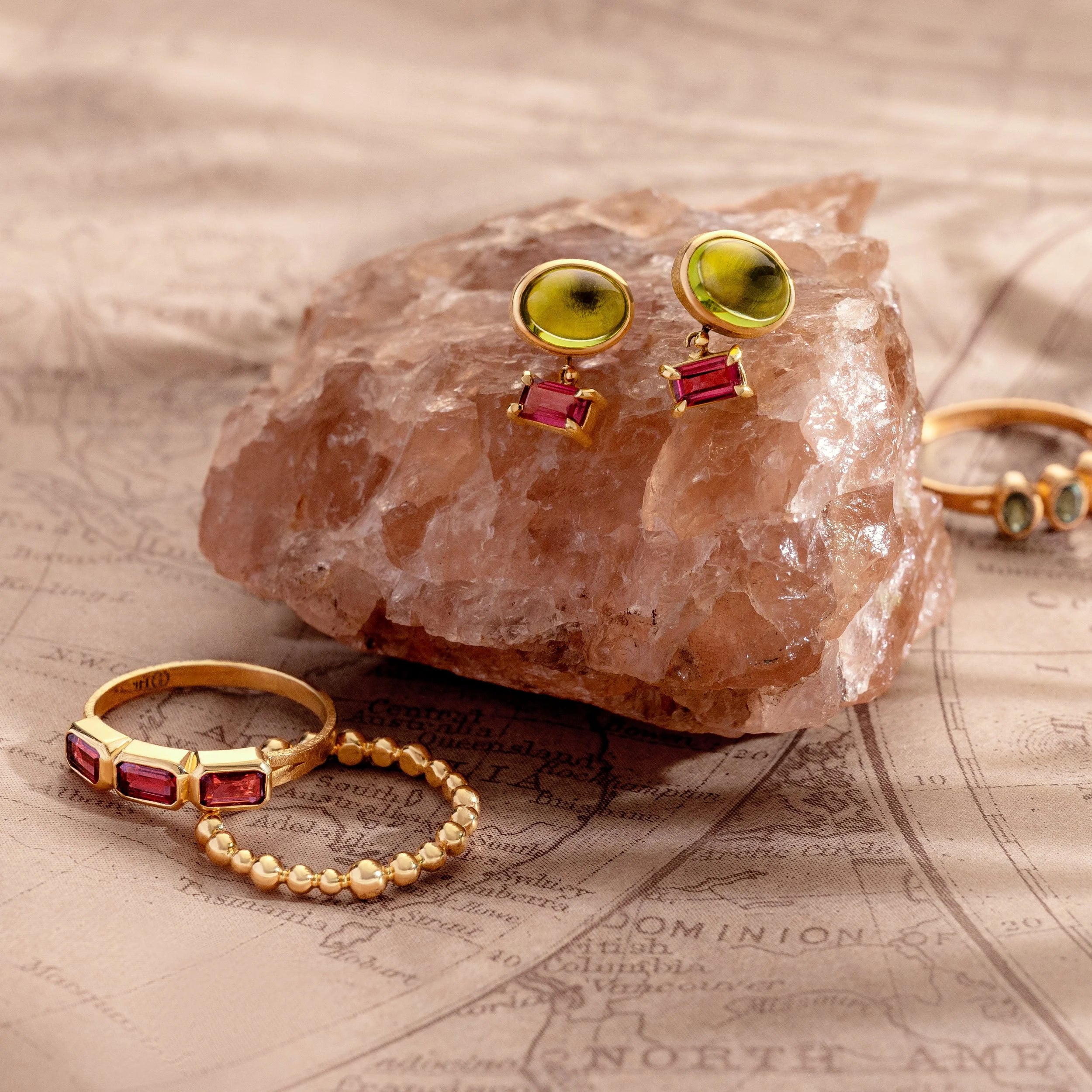 Gold rings with gemstones on a rock and map background