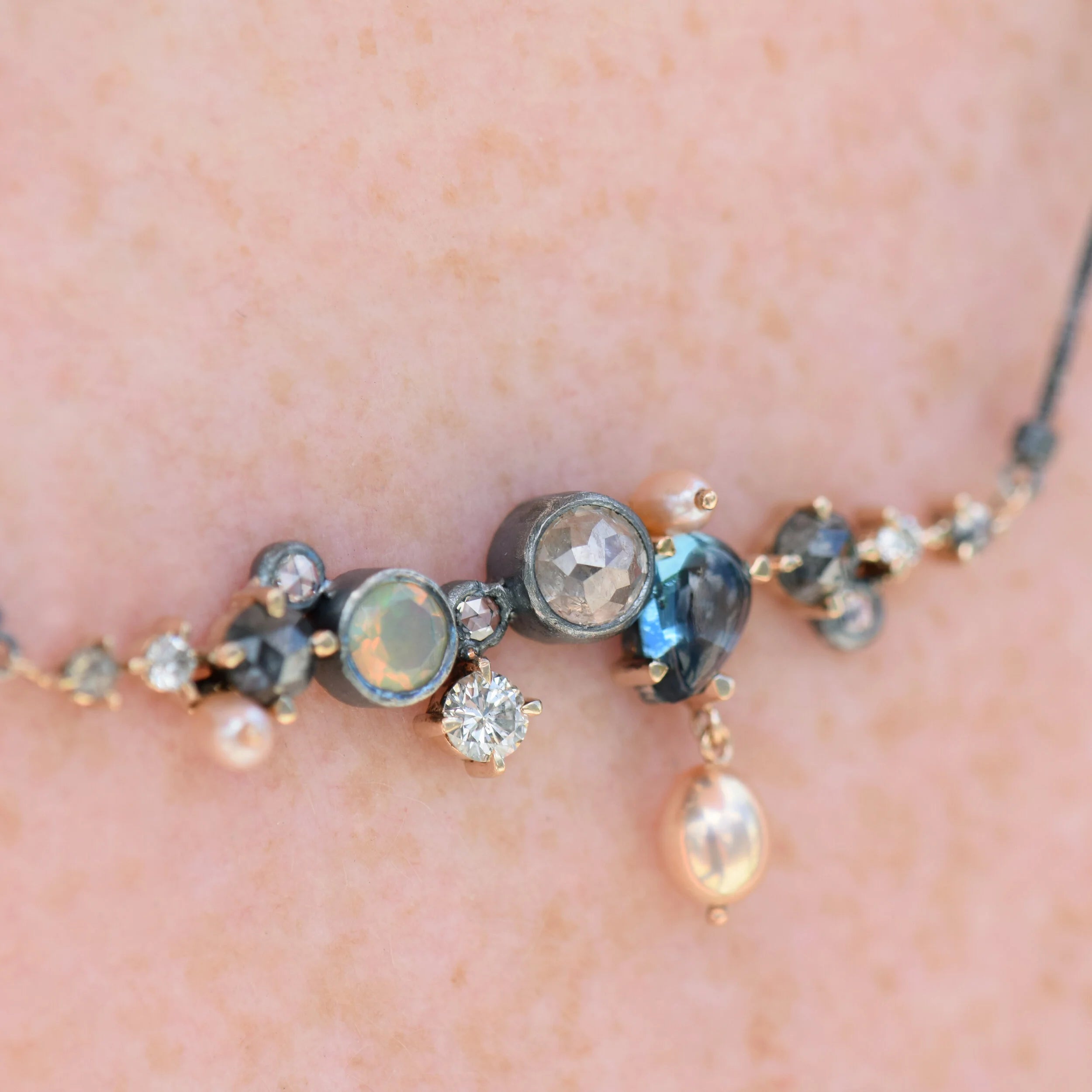 Necklace with gemstones and pearls on a person's neck