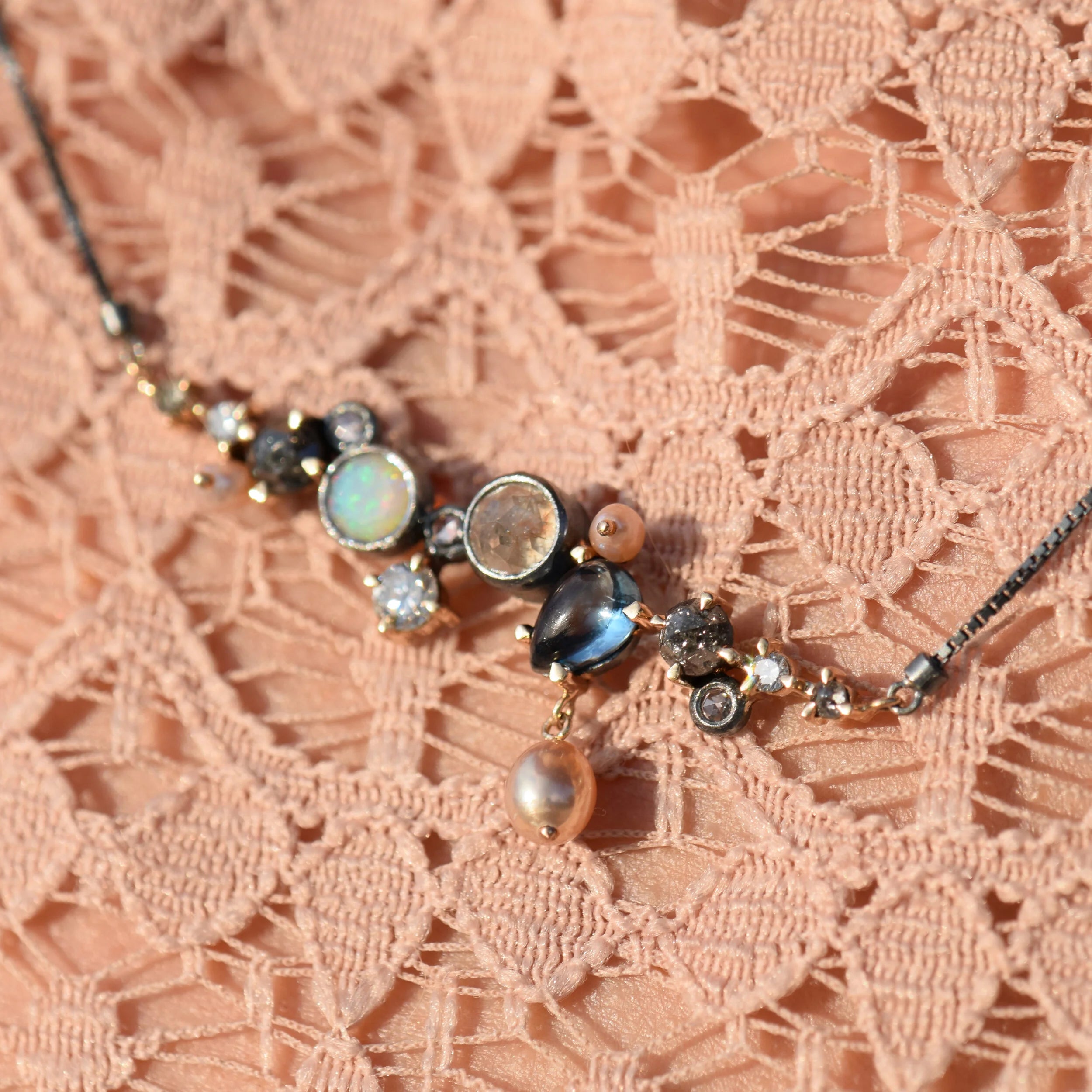 Necklace with various gemstones on a pink lace background