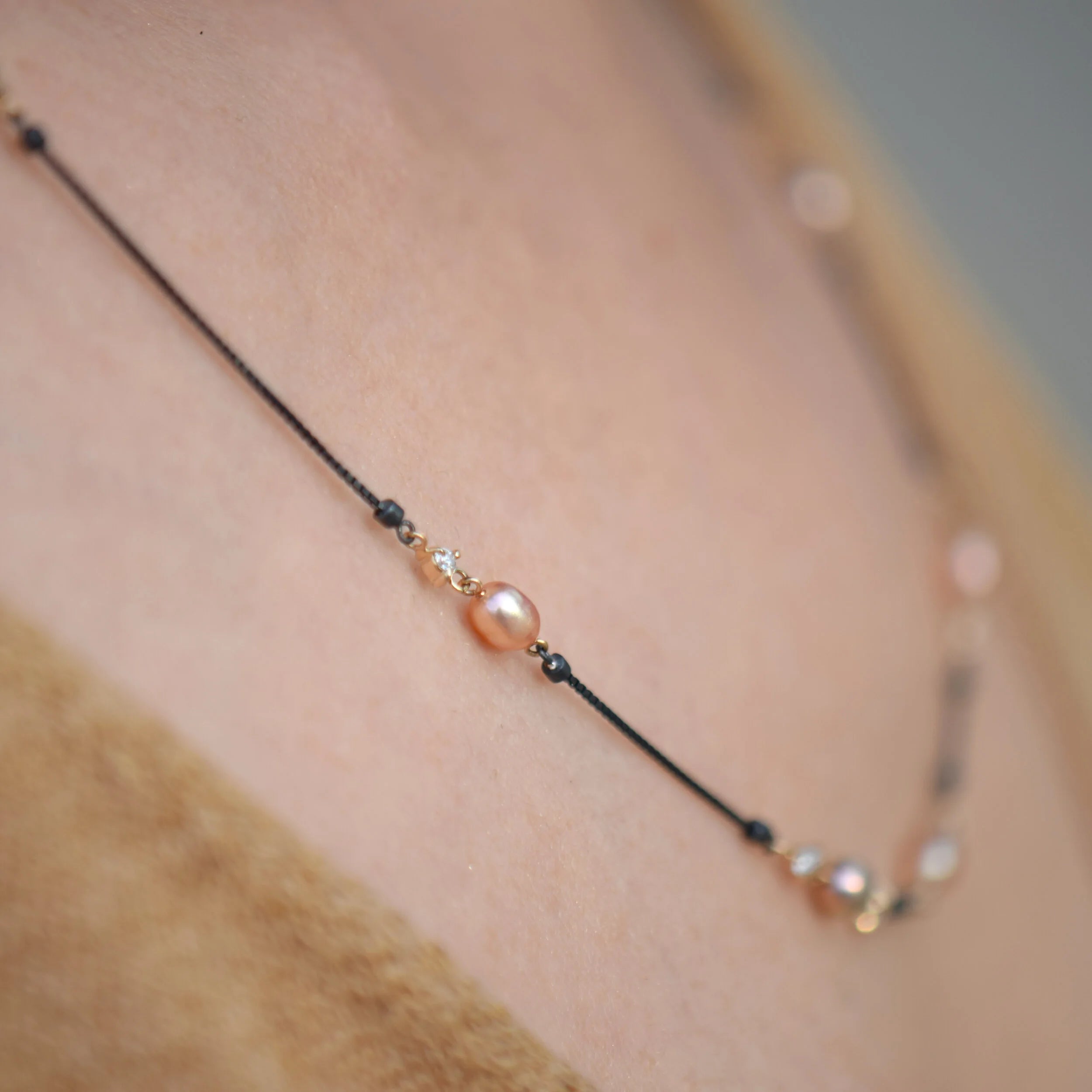 Necklace with pearl beads on a person's neck against a neutral background