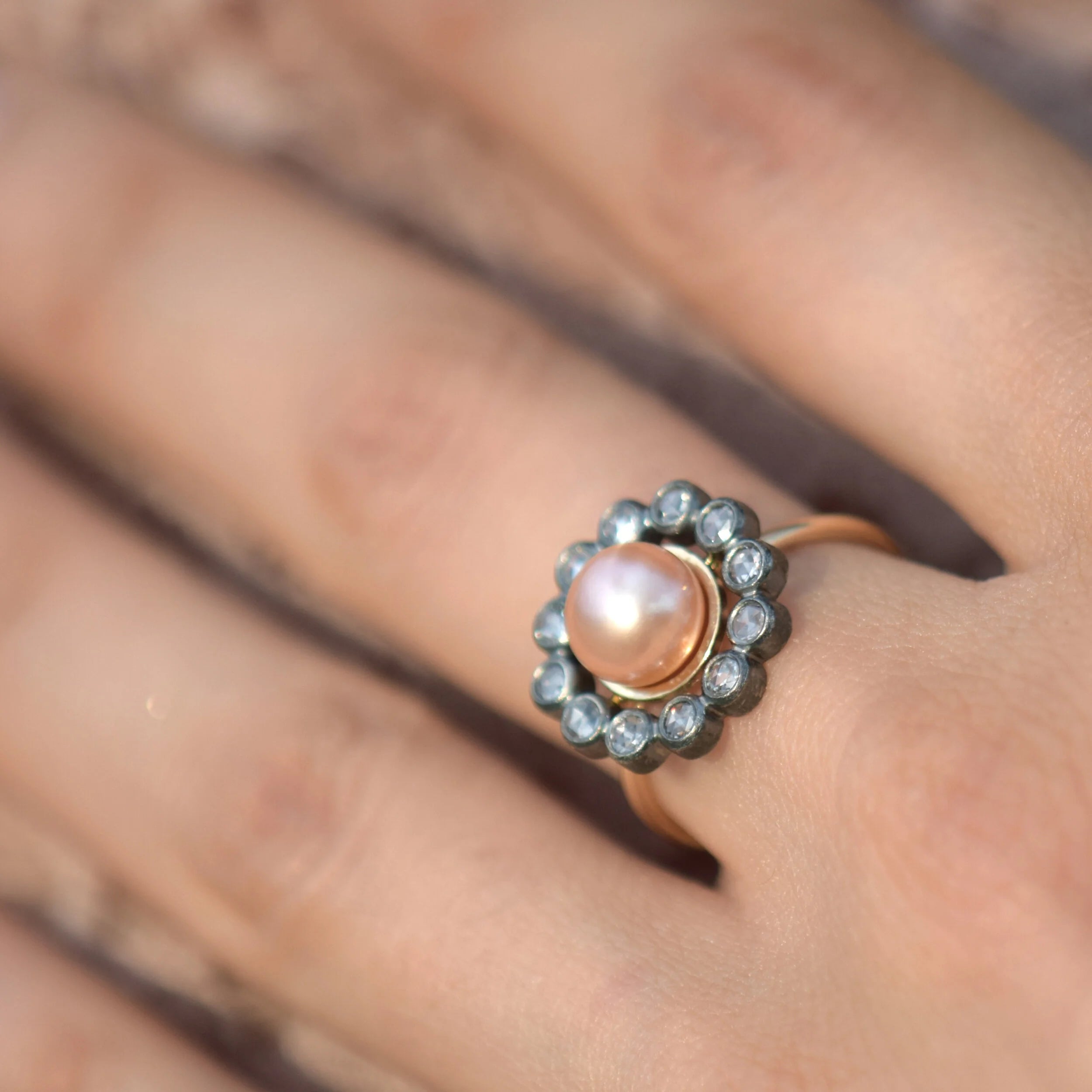 Ring with a pink pearl and diamond stones on a finger