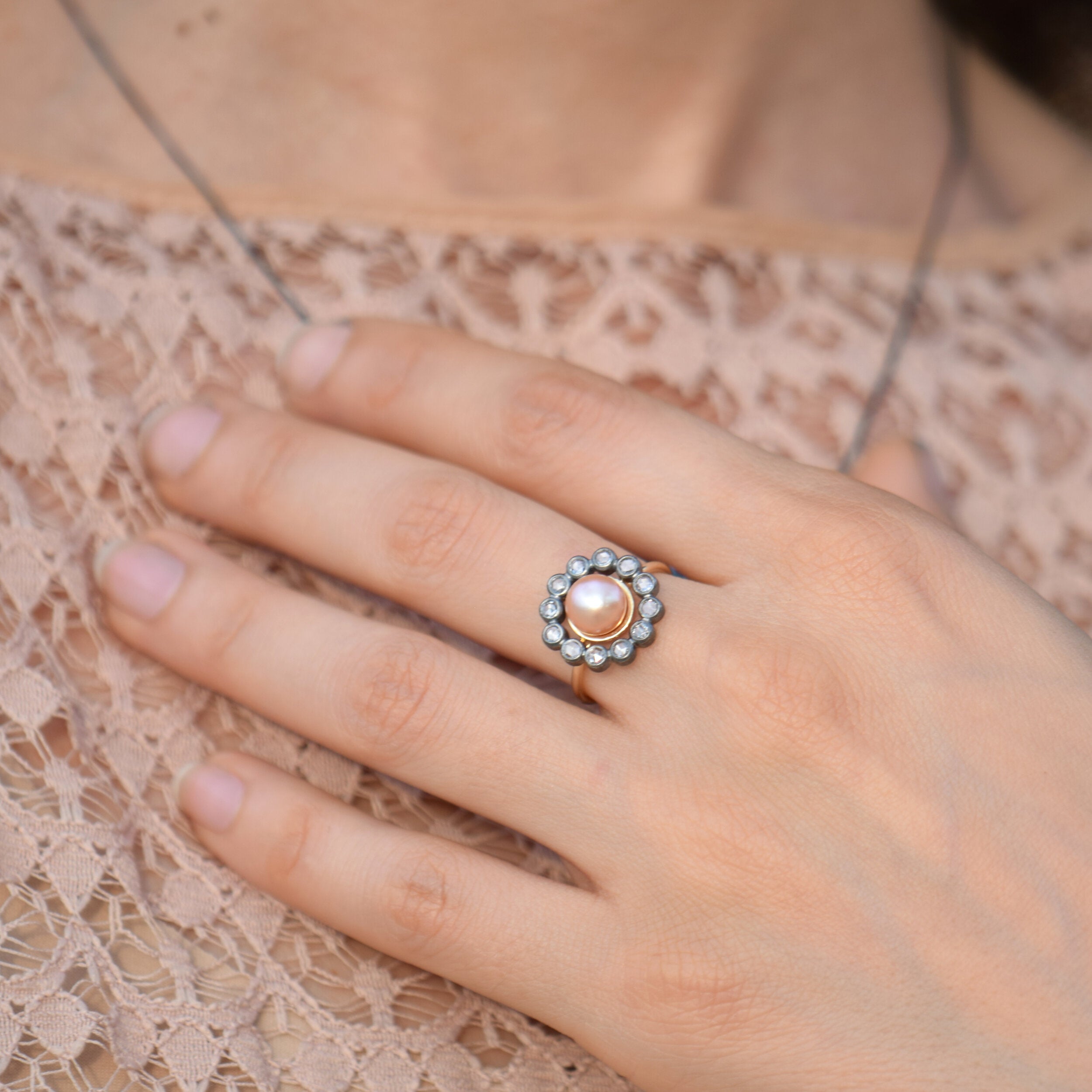 Hand wearing a decorative ring on a lace fabric background