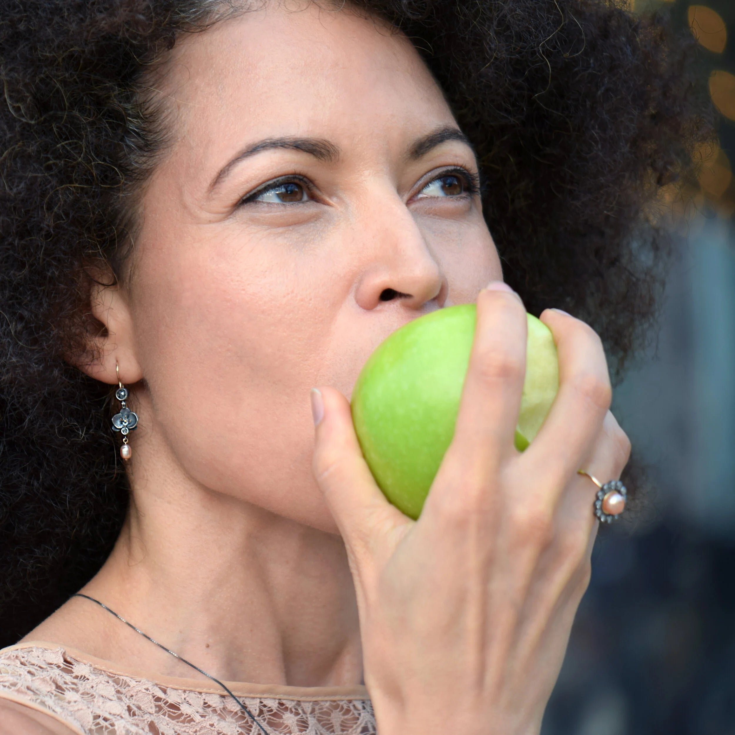 Woman eating a green apple with a blurred background